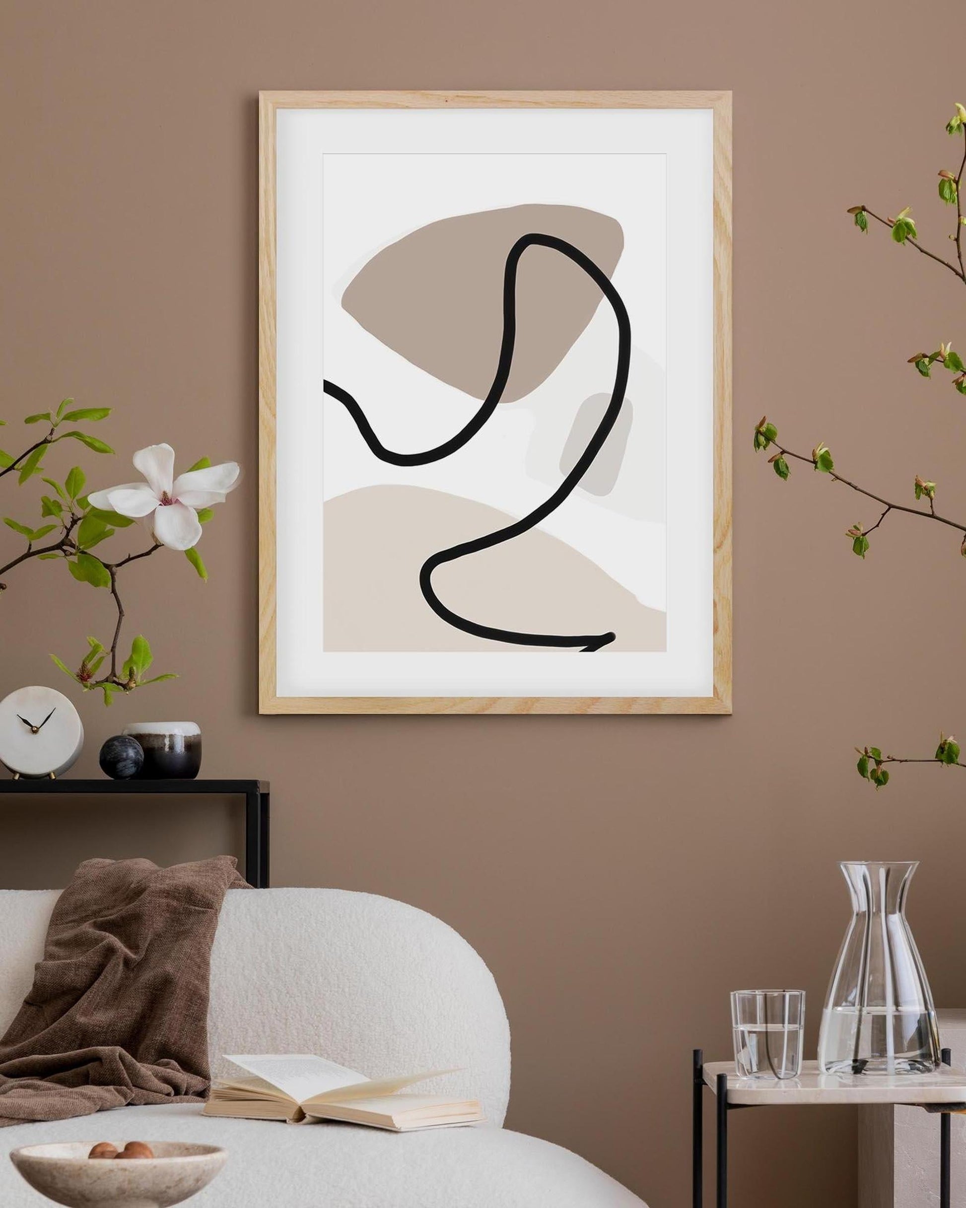 Abstract art print in a wooden frame on a wall with a living room setting.