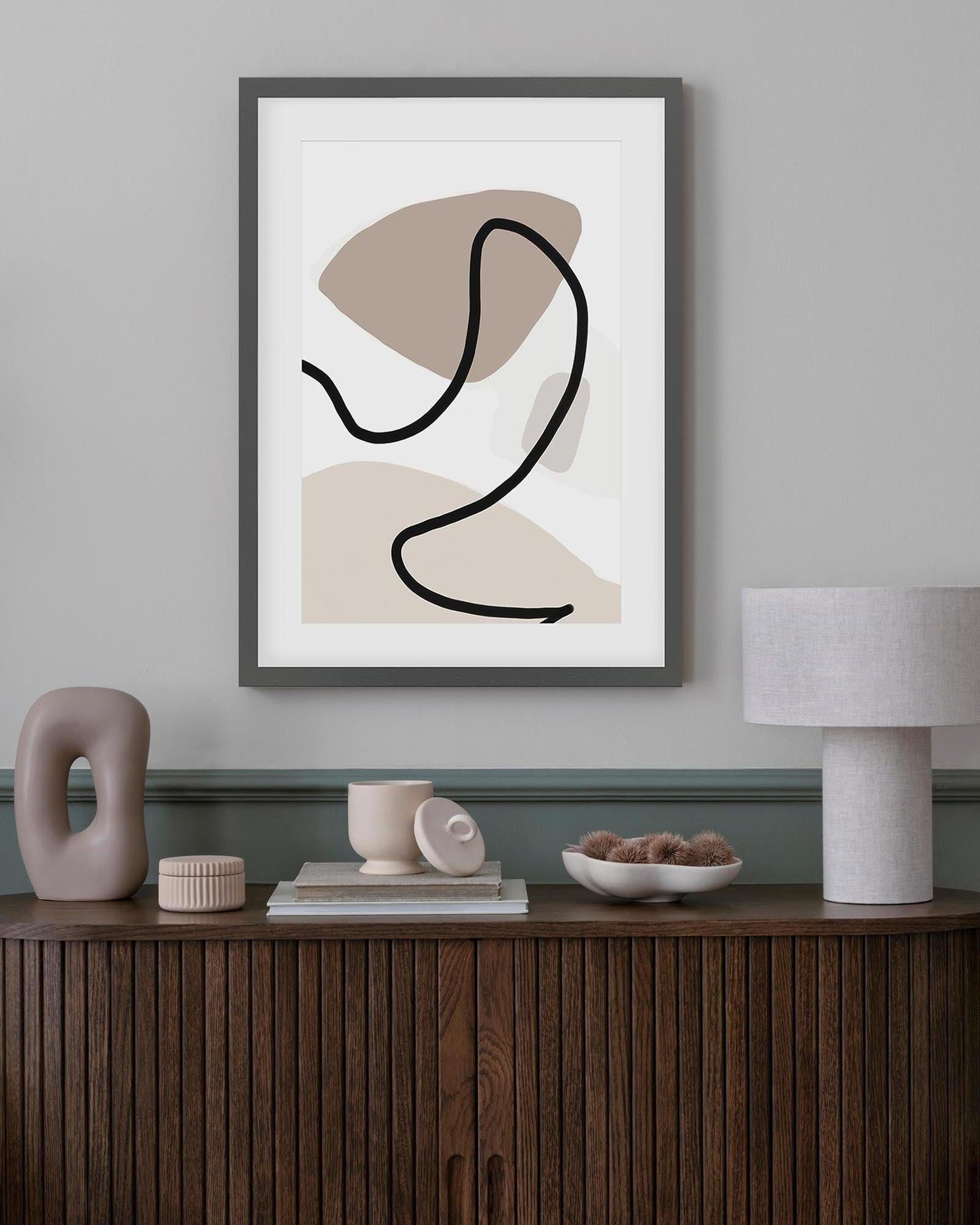 Abstract art print in a modern interior setting with decor items on a wooden console.