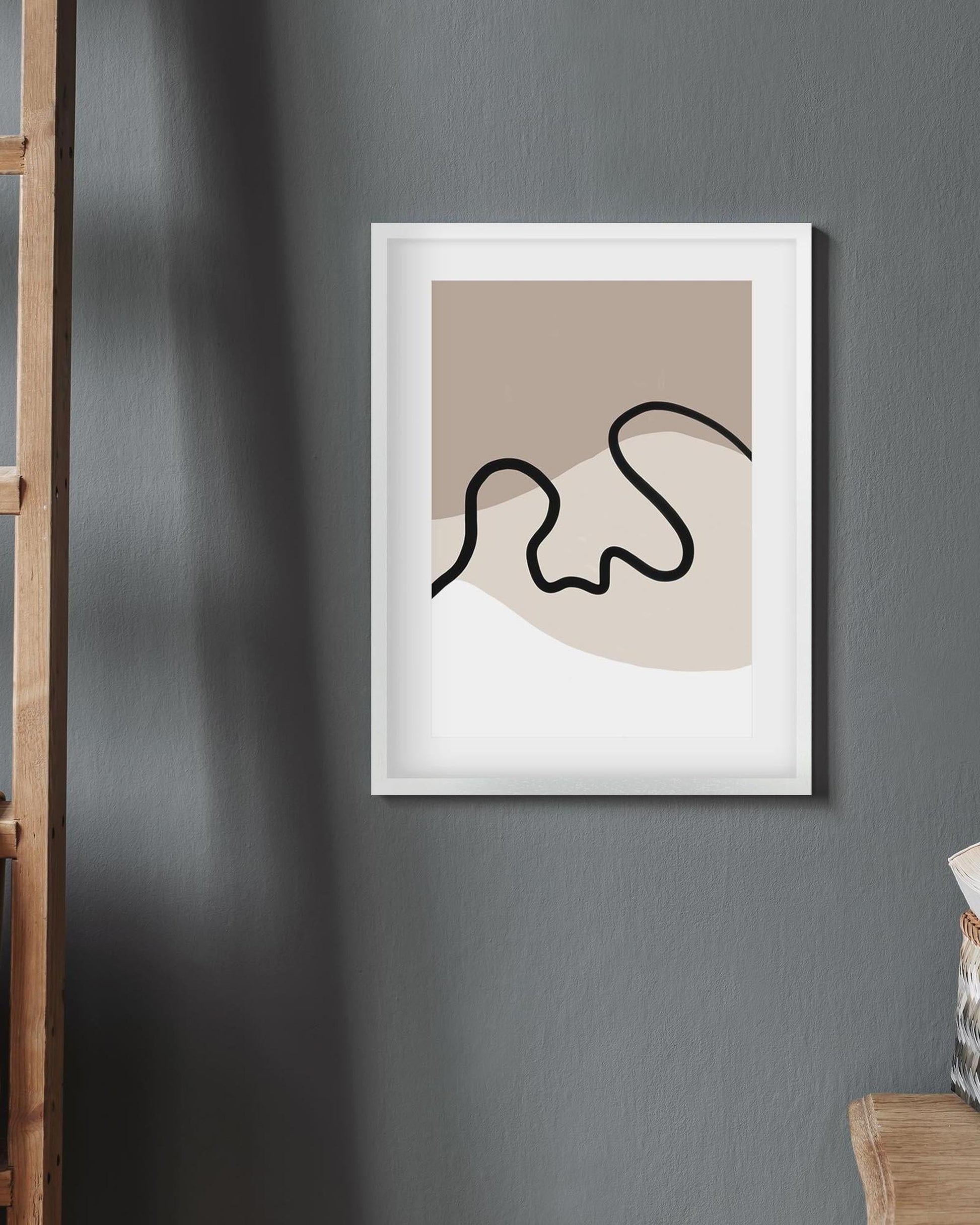 Framed abstract art print on a gray wall with a wooden ladder and chair in the corner.