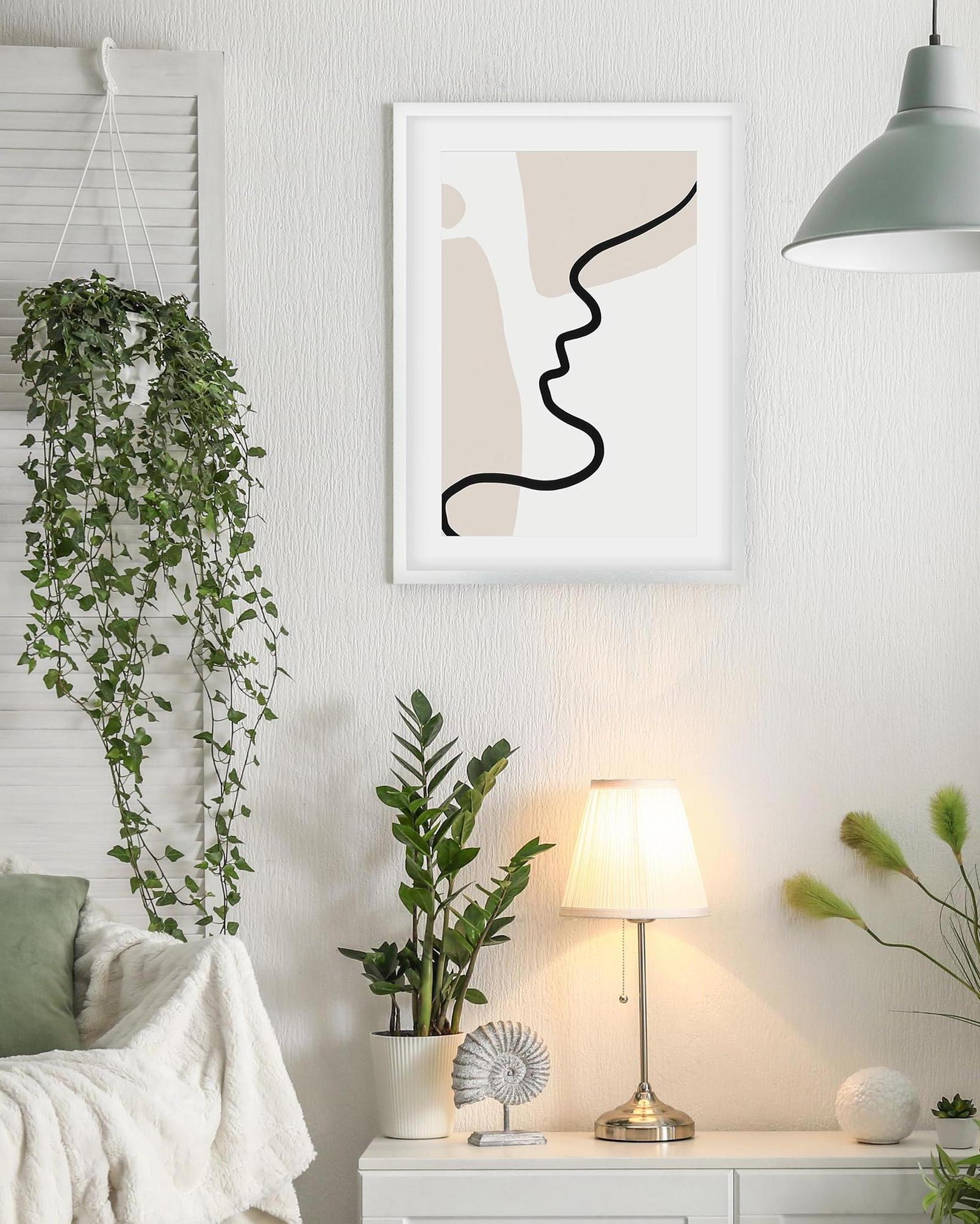Modern interior with abstract art, plants, and a lamp on a white wall.