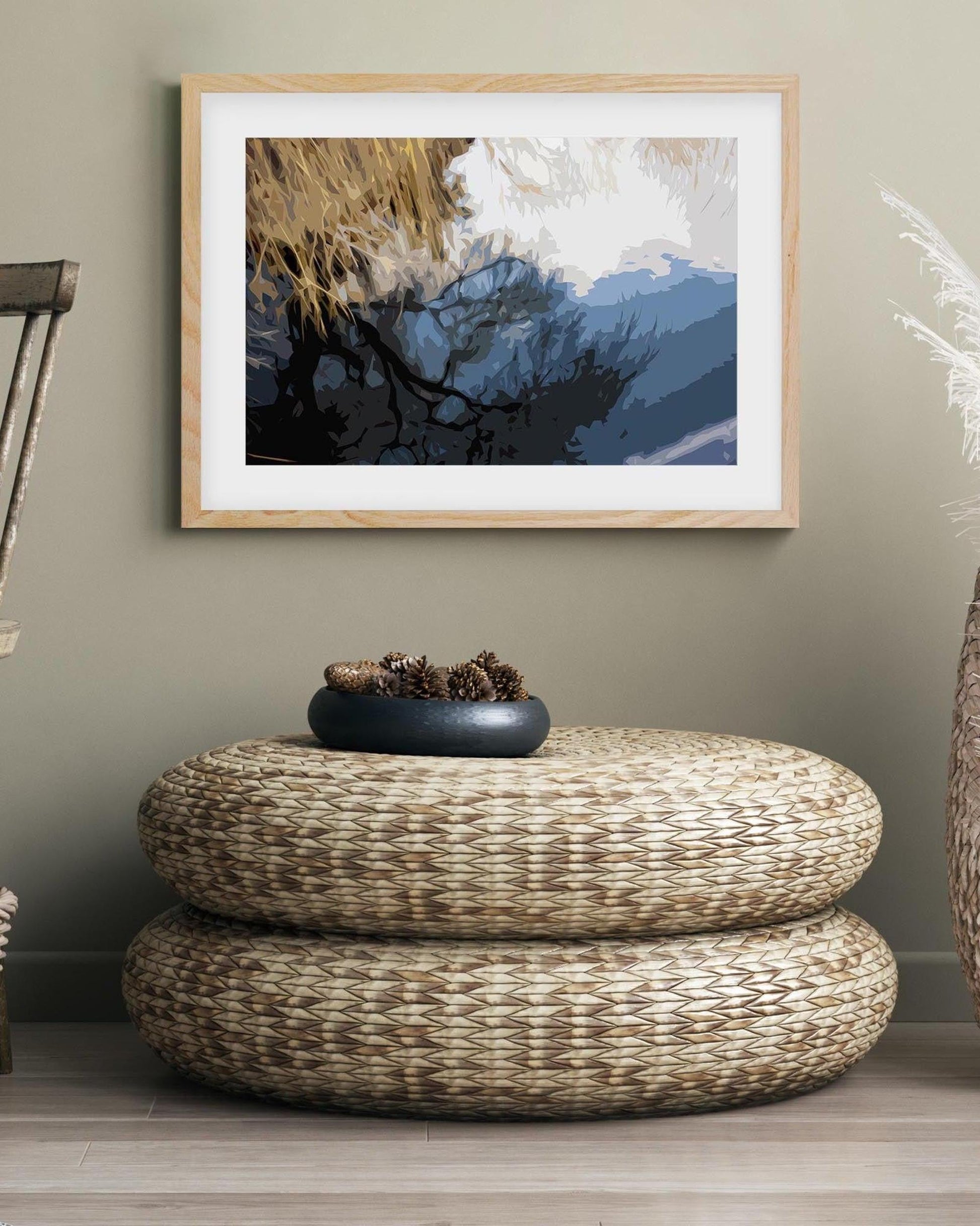 Woven ottoman with a decorative bowl on top, framed artwork on the wall.