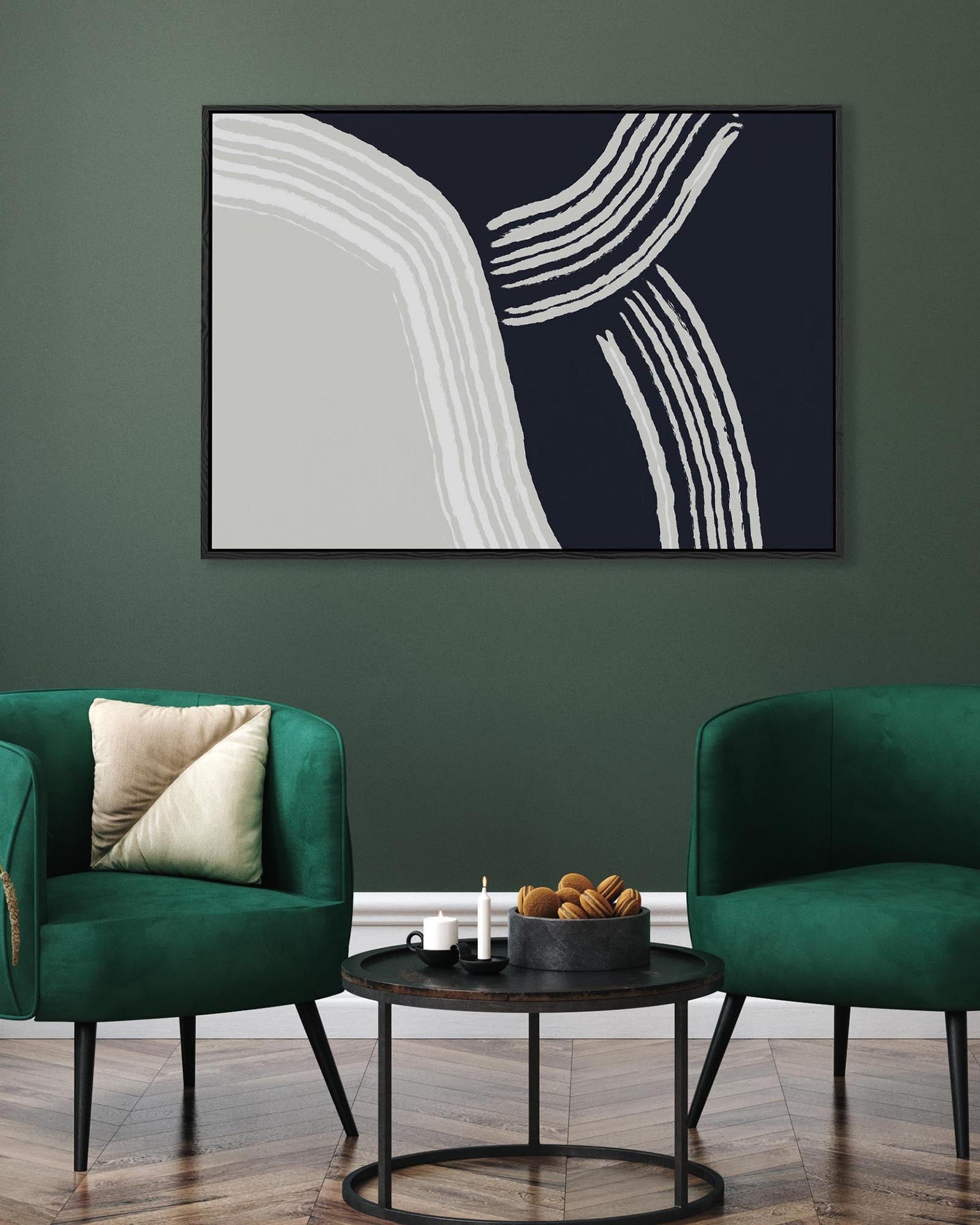 Modern living room with abstract art on a green wall, two green chairs, and a small round table.