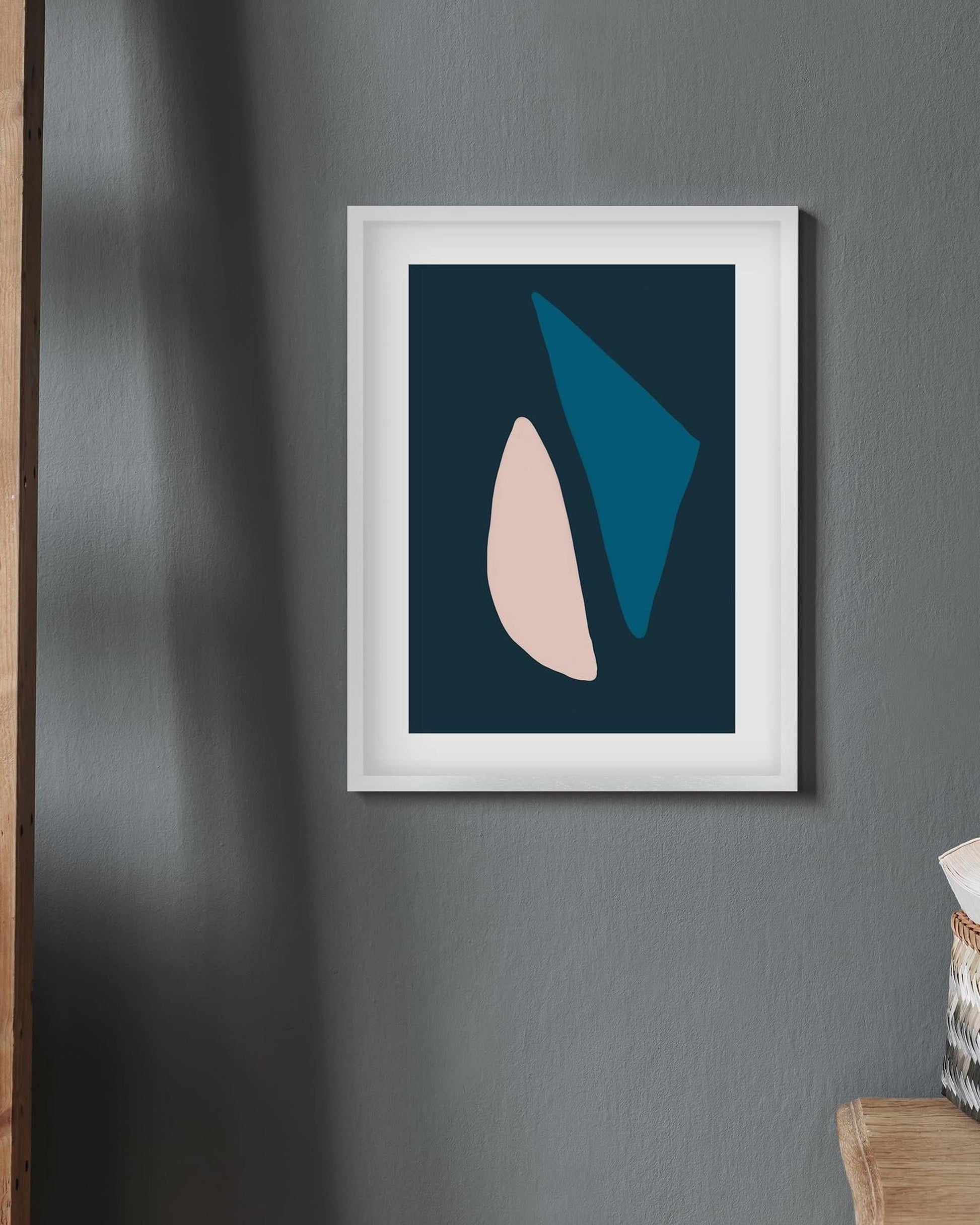 Framed abstract art print with geometric shapes on a gray wall.
