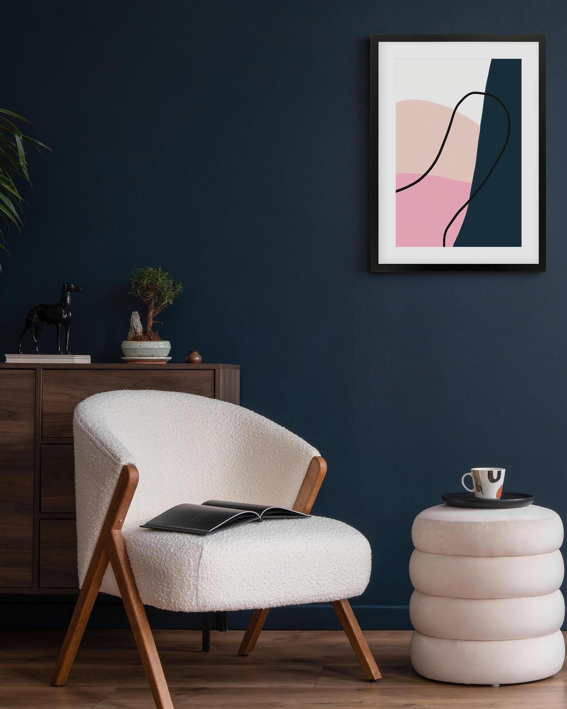 Modern living room with a white armchair, side table, and abstract art on the wall.