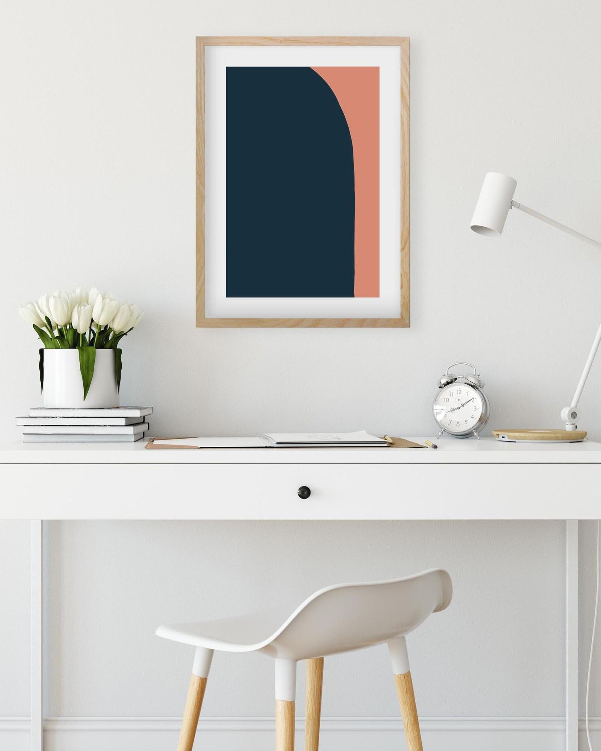 Framed abstract art on a wall above a desk with a chair.