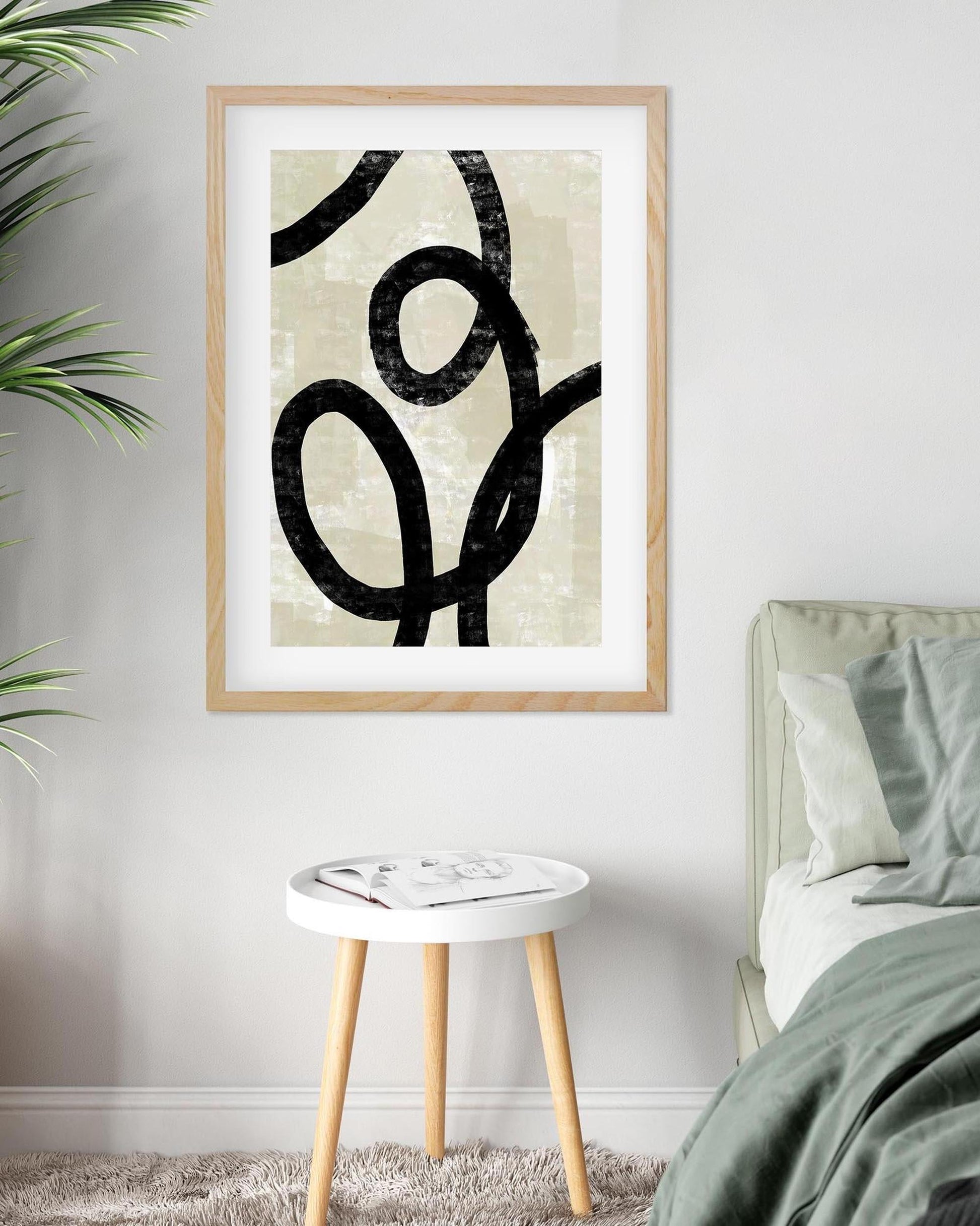 Framed abstract art print on a wall above a bed in a bedroom.