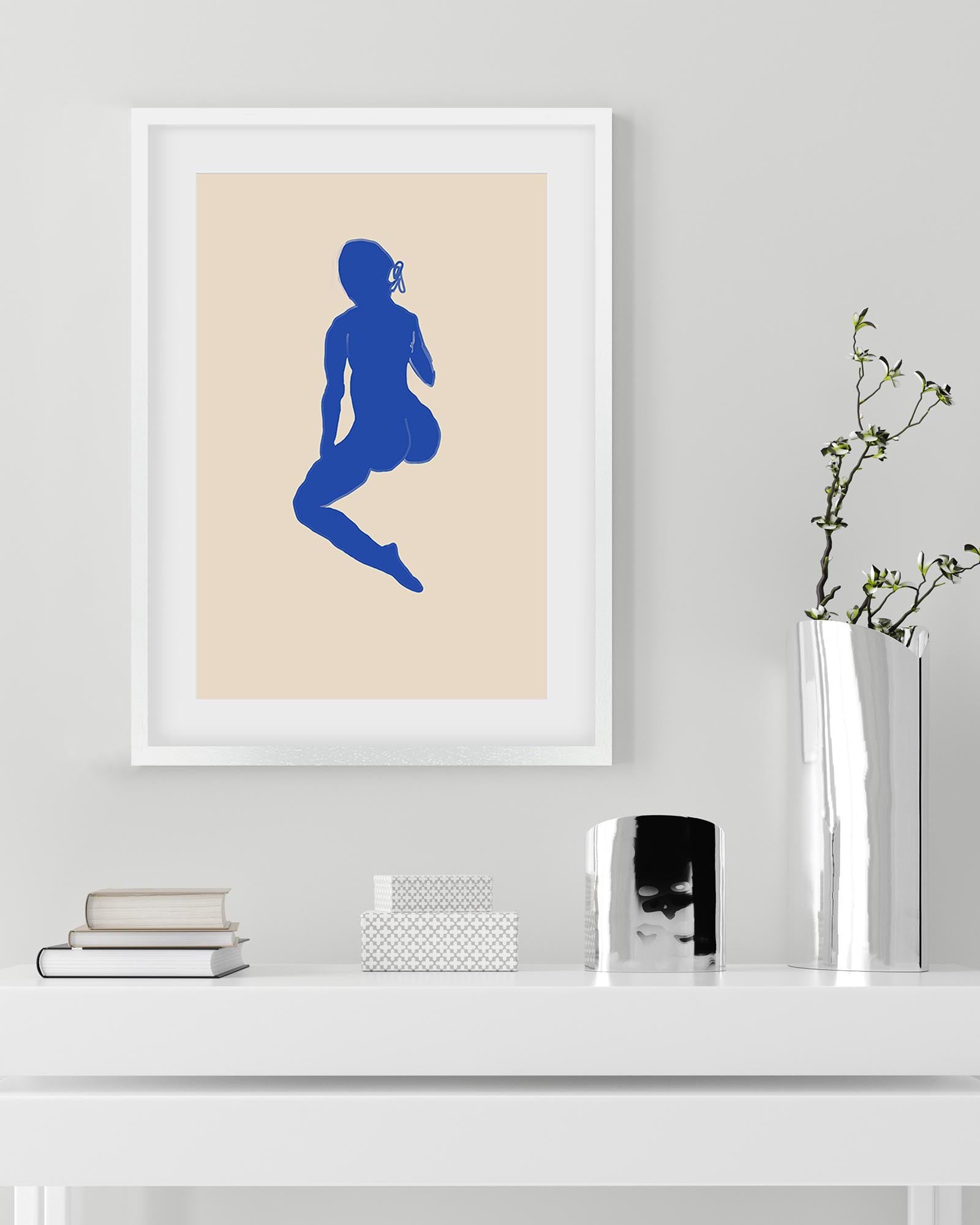 Framed art print of a blue silhouette on a beige background, displayed on a white shelf.
