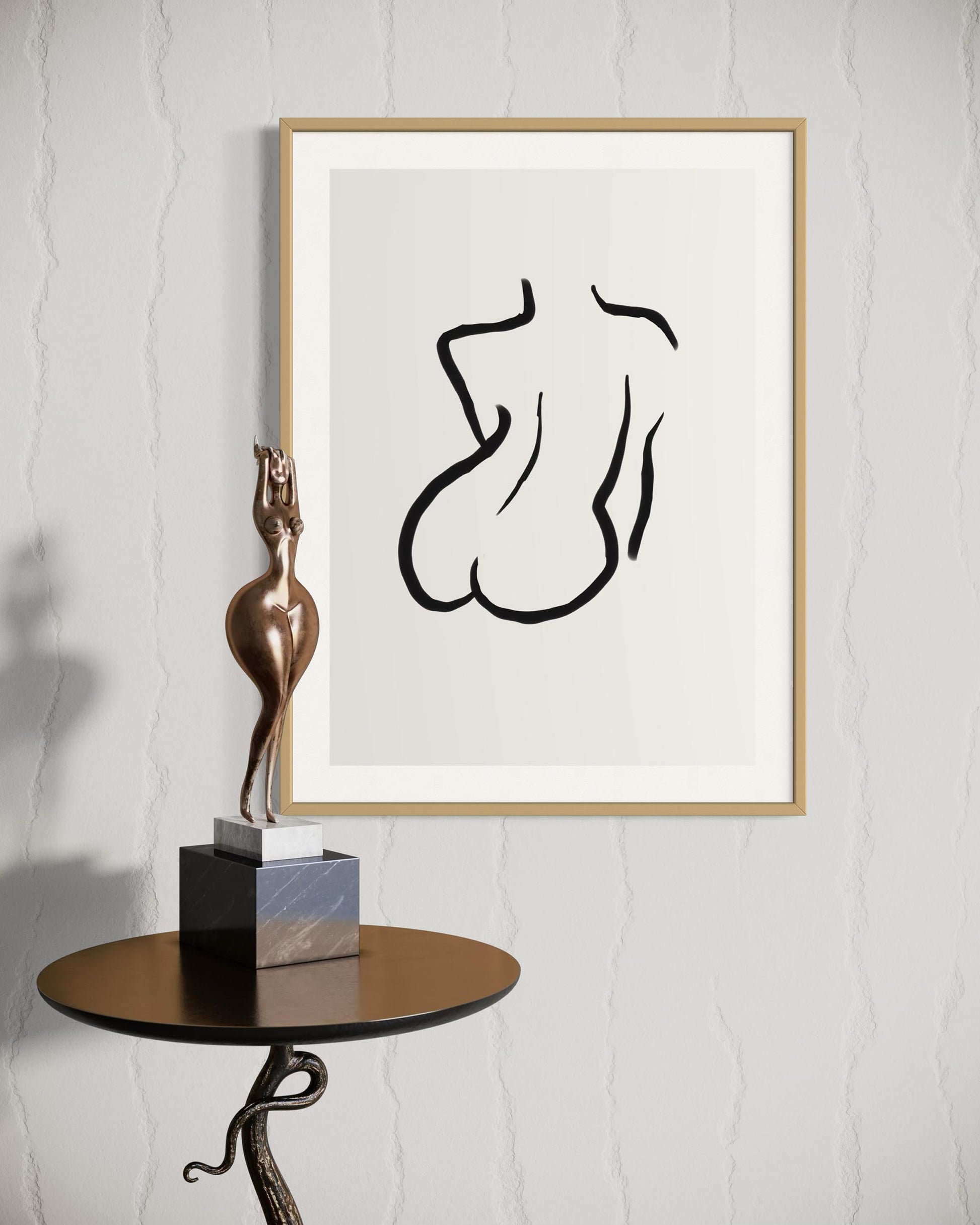 Framed abstract artwork of a nude figure on a white wall with a bronze sculpture on a table.