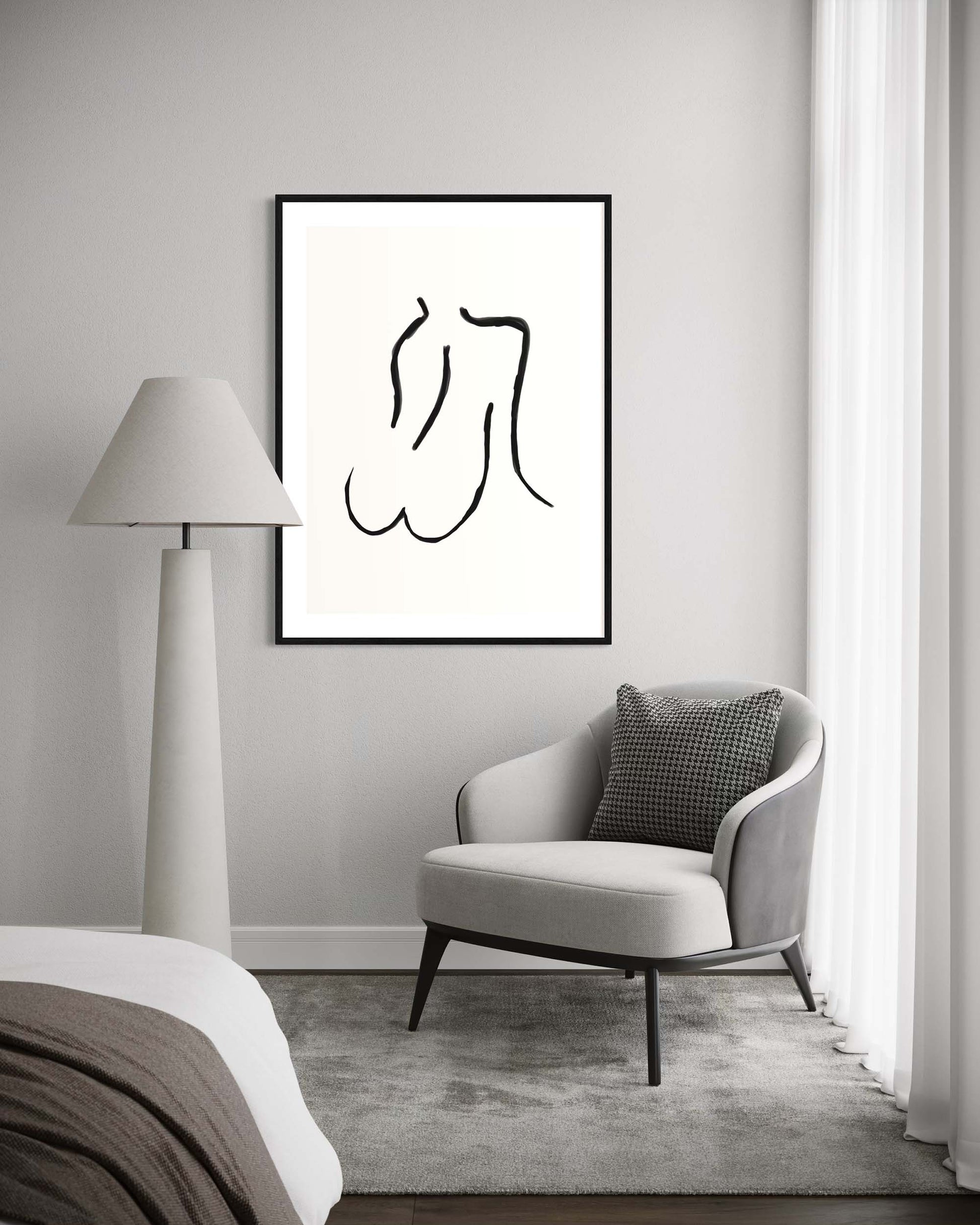 Modern interior with a chair, lamp, and framed black and white artwork on a gray wall.