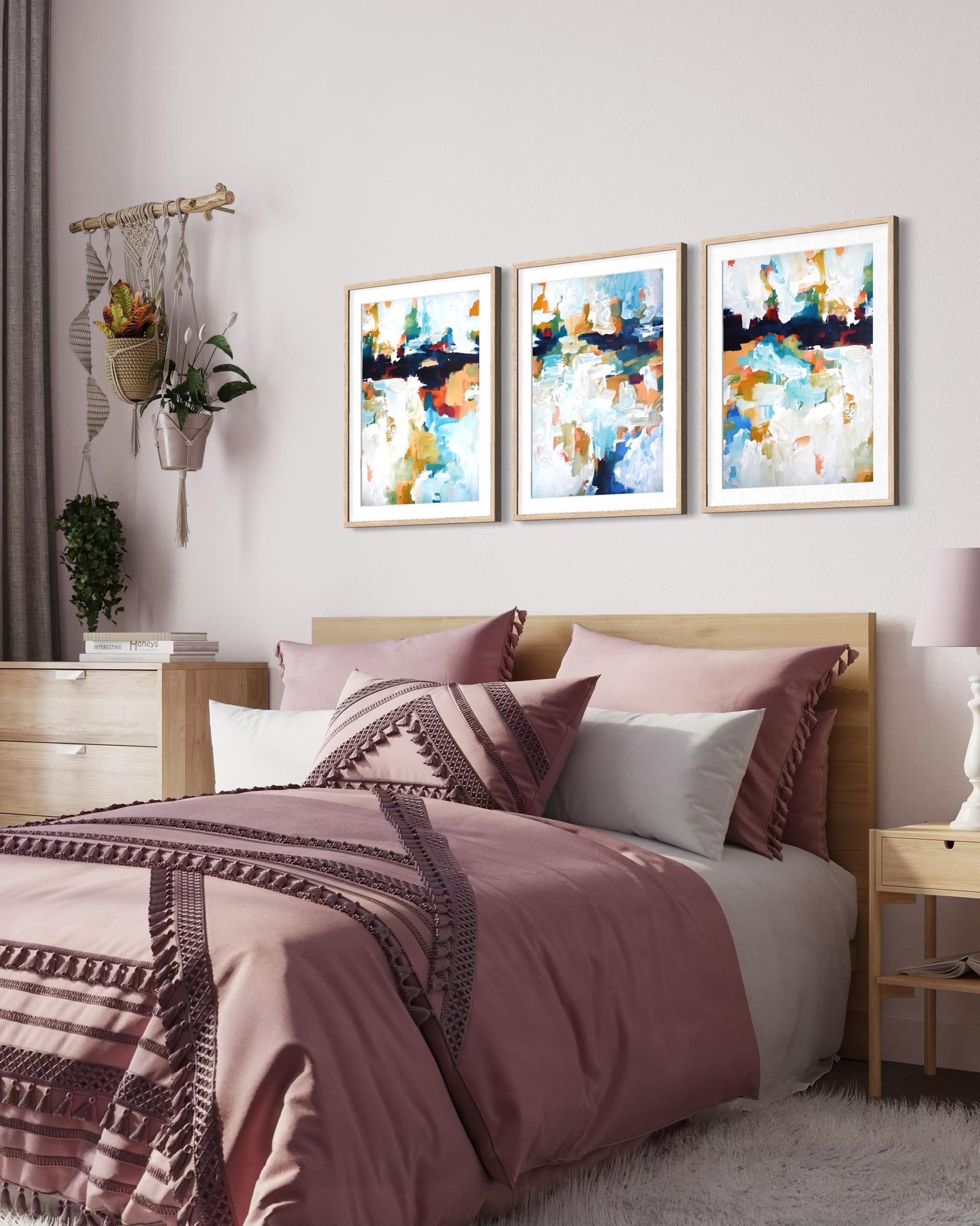 Bedroom with a bed featuring pink and brown bedding, three abstract art pieces on the wall, and a side table.