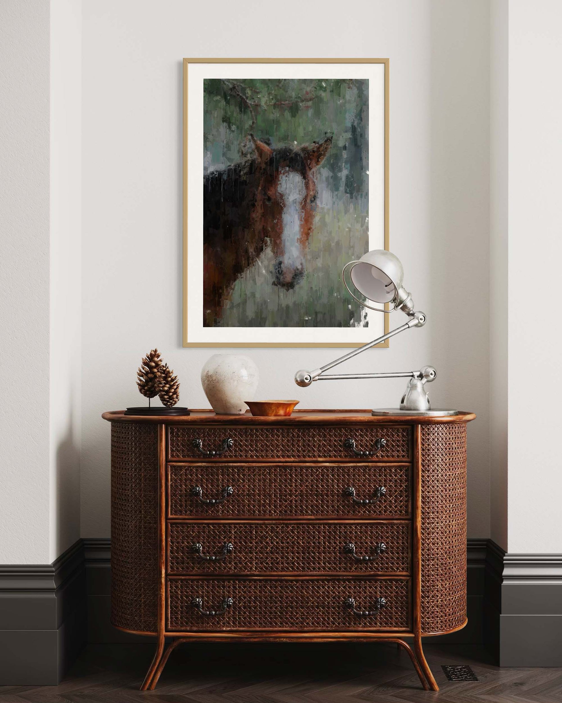 Wicker dresser with a lamp and decorative items against a wall with a framed horse painting.