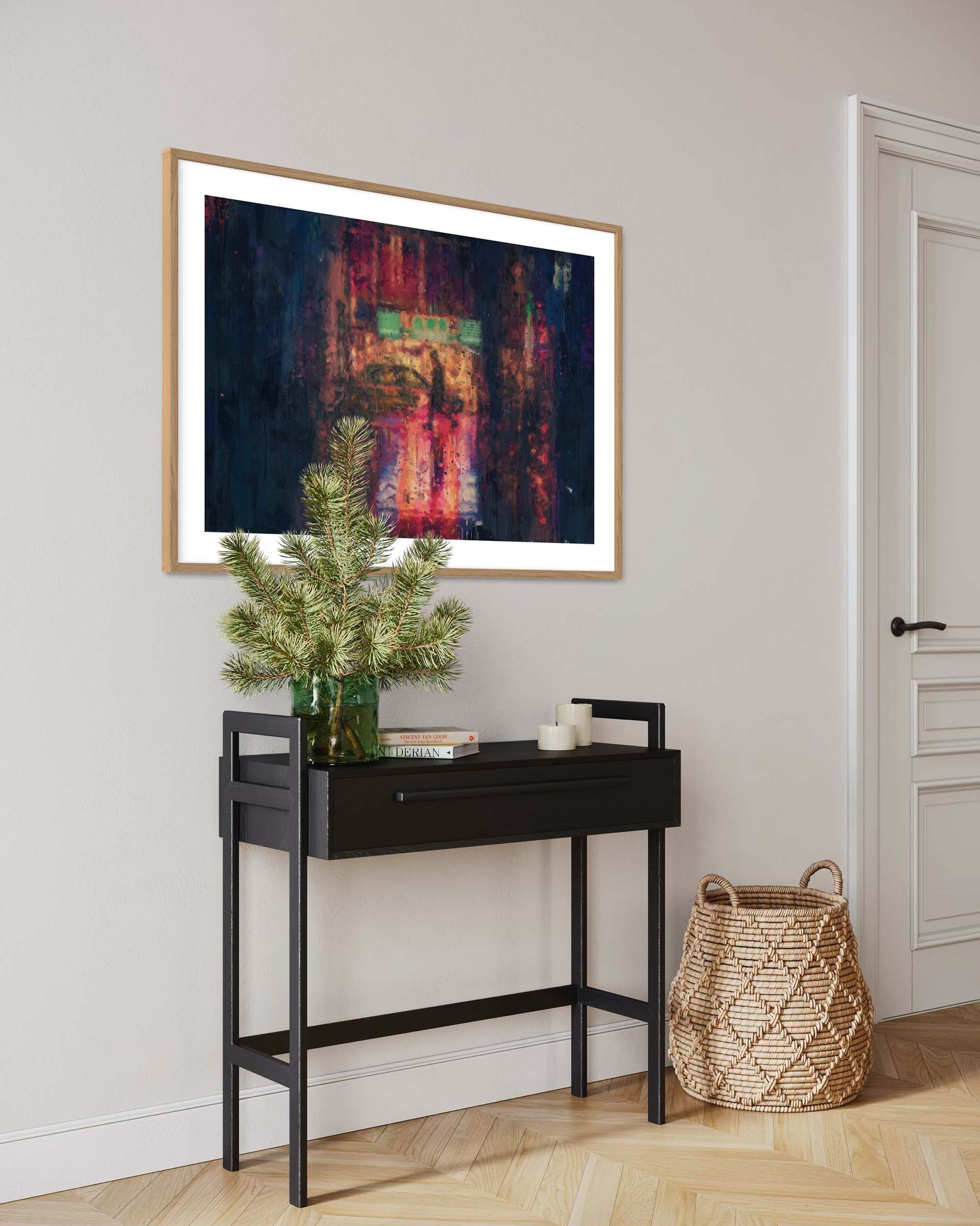 Modern interior with a black console table, decorative plant, and abstract framed art on a light gray wall.