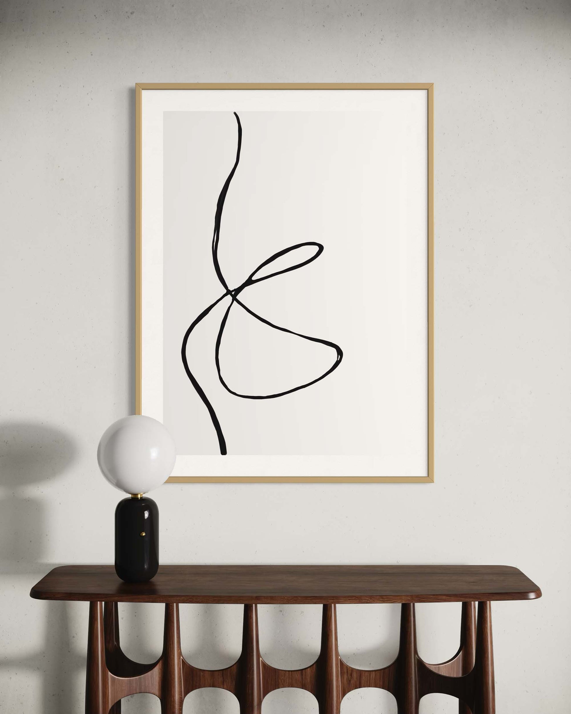 Abstract line art in a wooden frame on a white wall above a wooden console table.