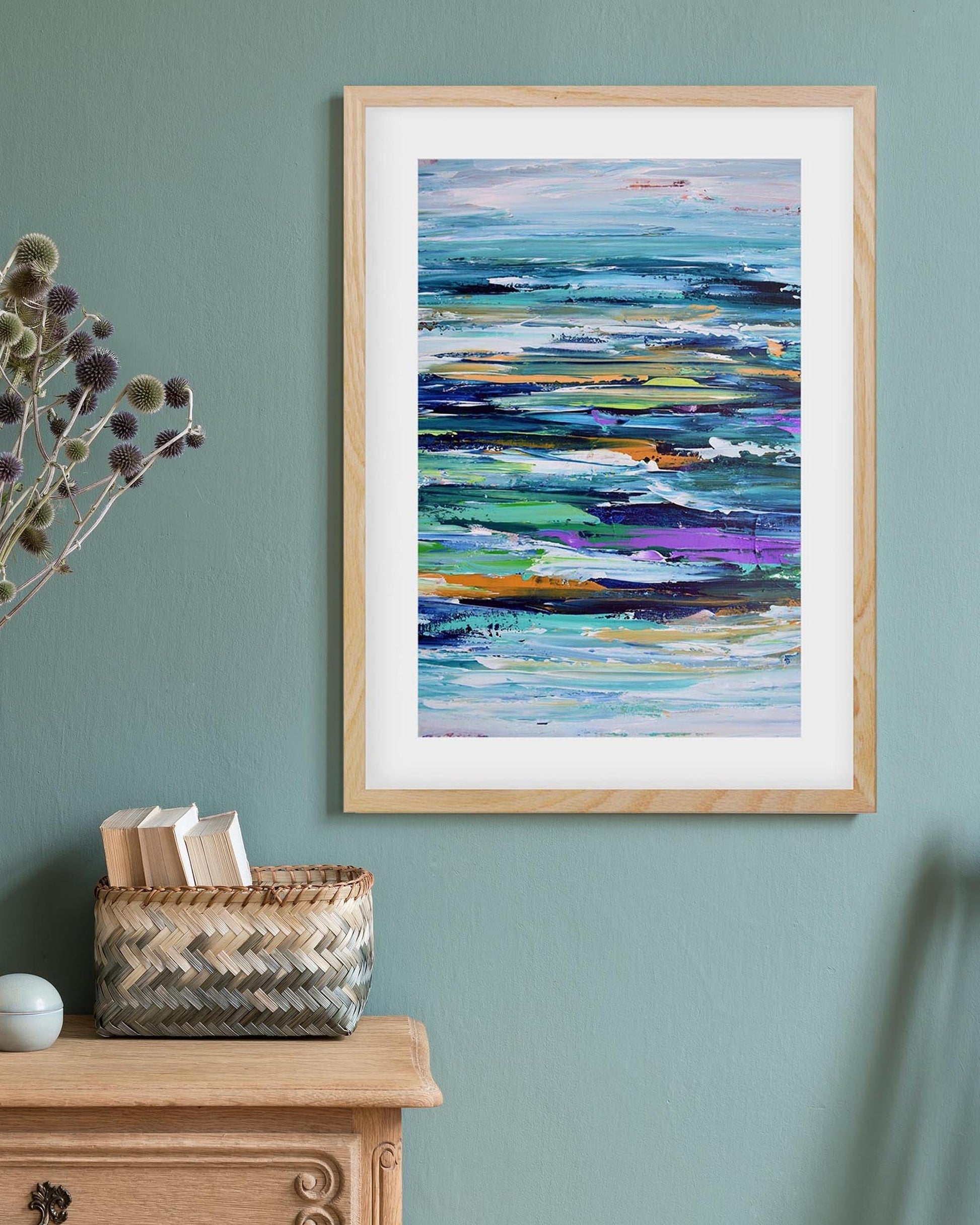 Framed abstract painting on a wall above a wooden cabinet with decorative items.