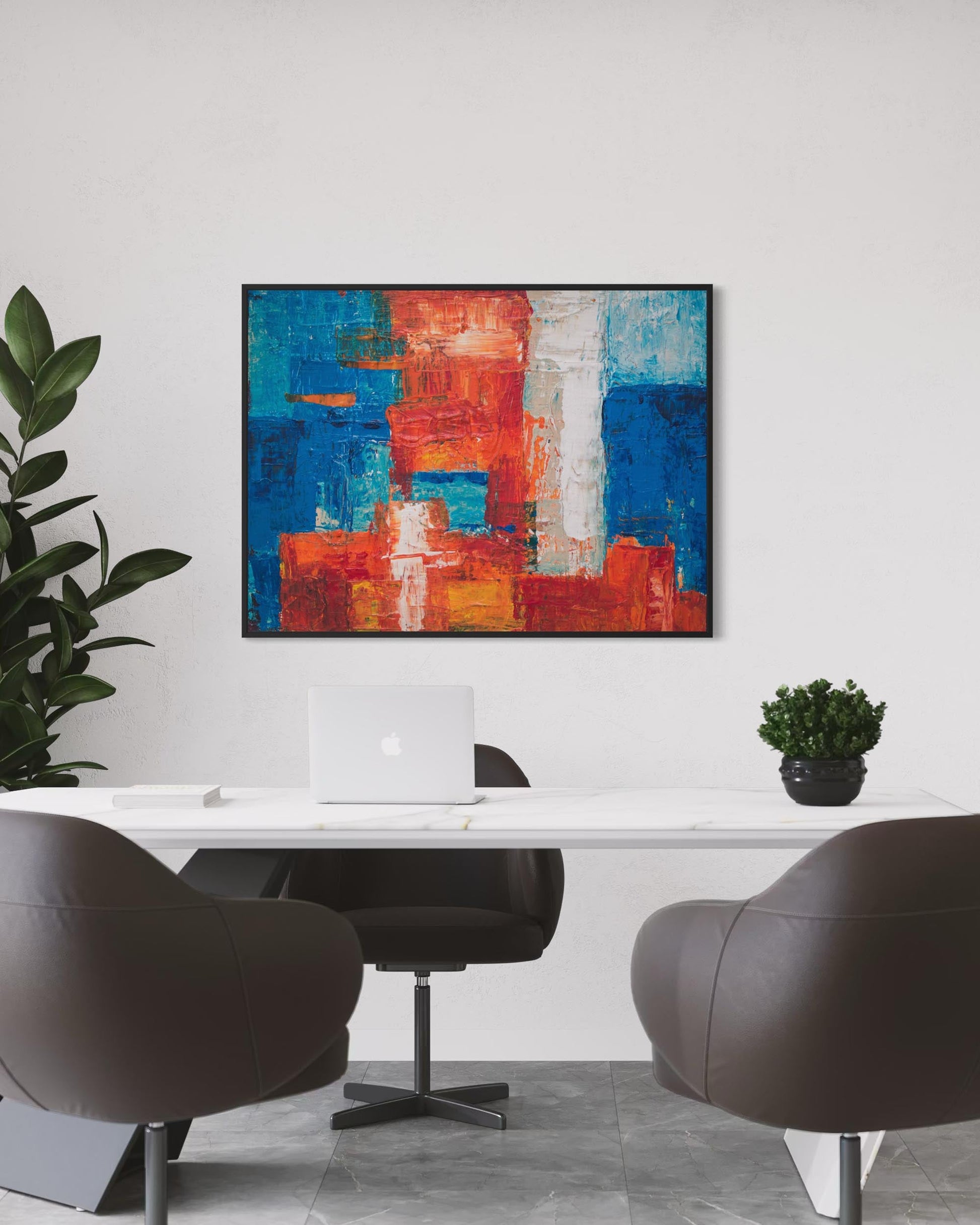 Modern office interior with abstract art, chairs, and a laptop.