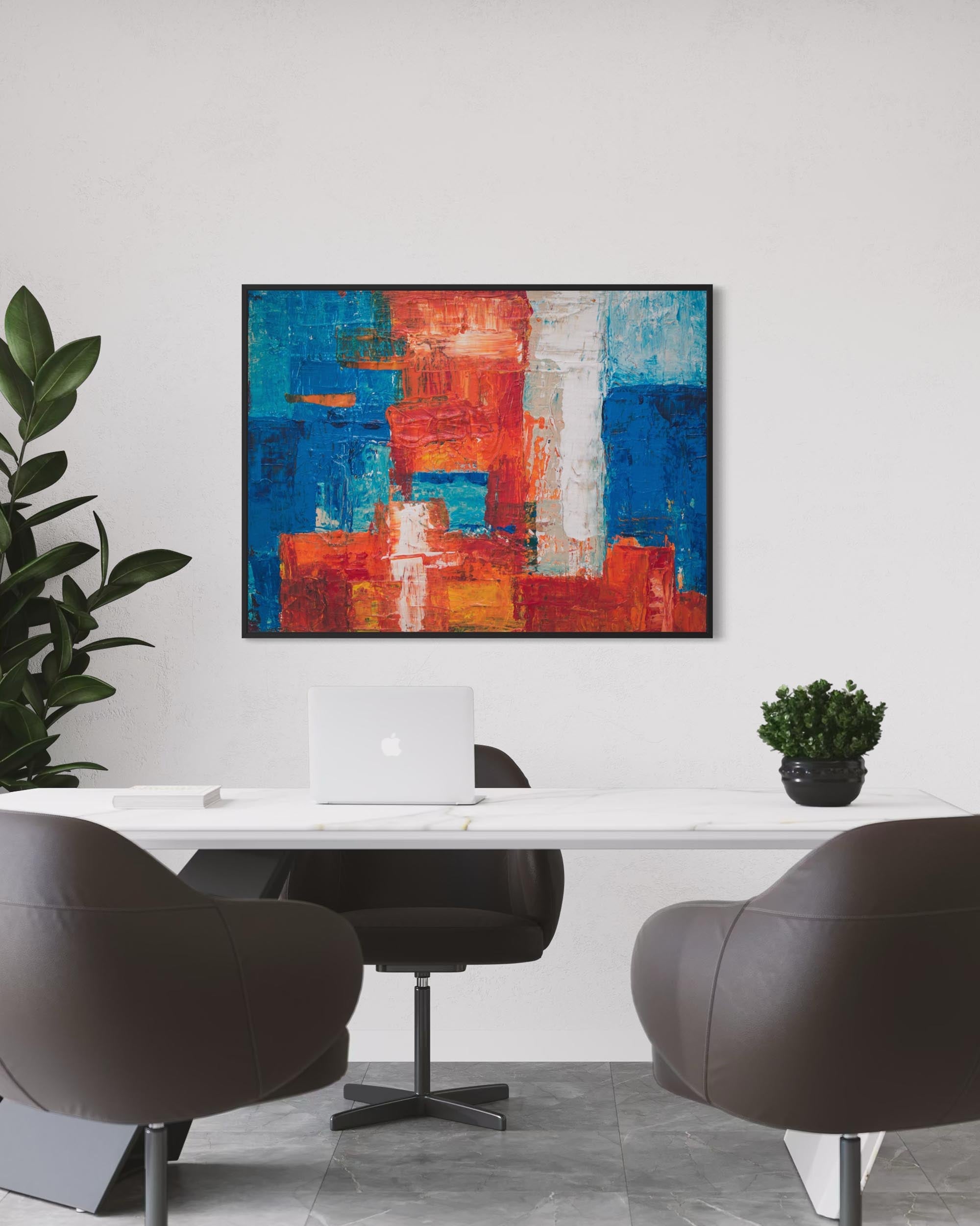 Modern office interior with abstract art, chairs, and a laptop.