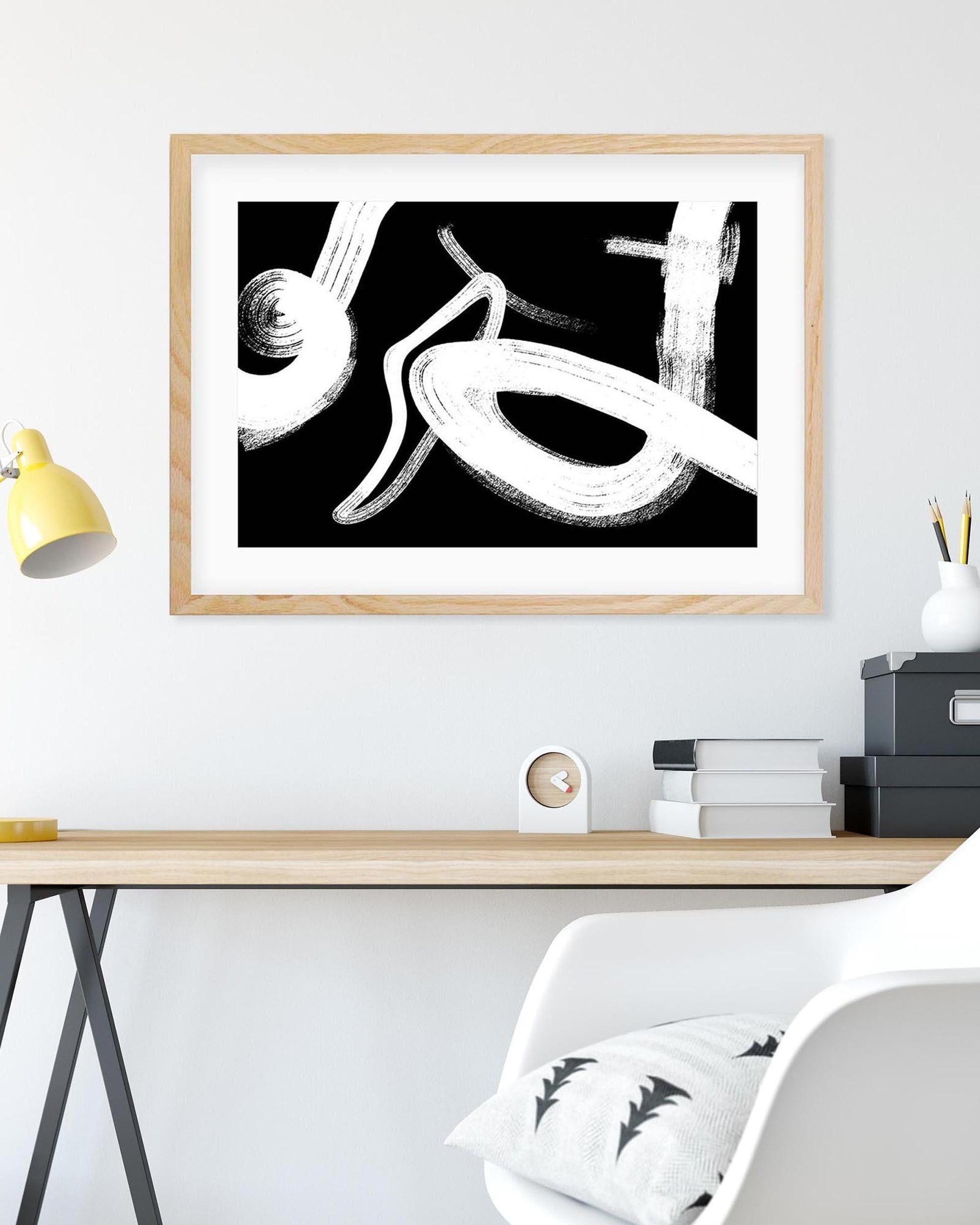 Framed abstract artwork on a wall above a desk with office items.