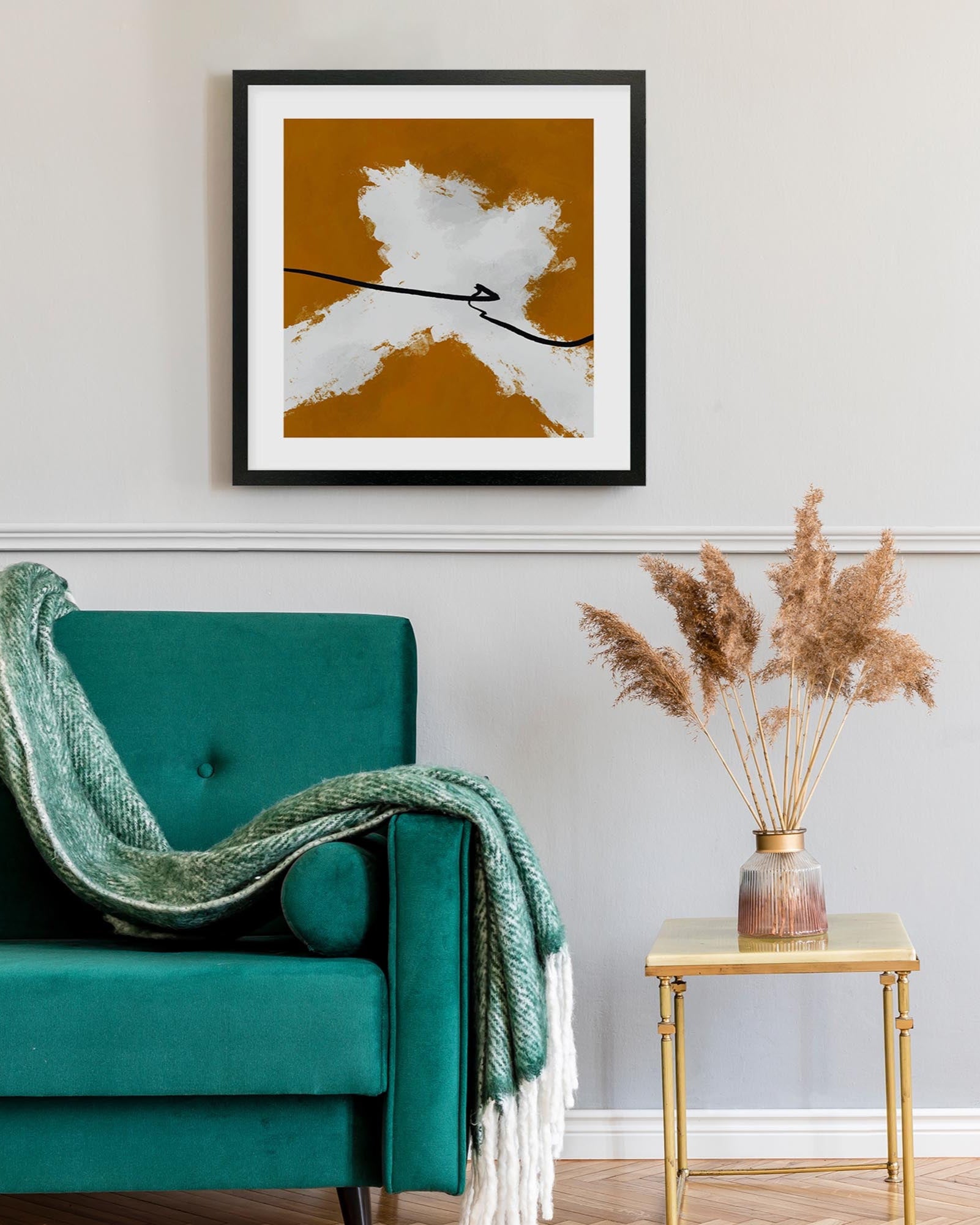 Teal armchair with a green blanket, framed abstract art on the wall, and a small table with dried plants.