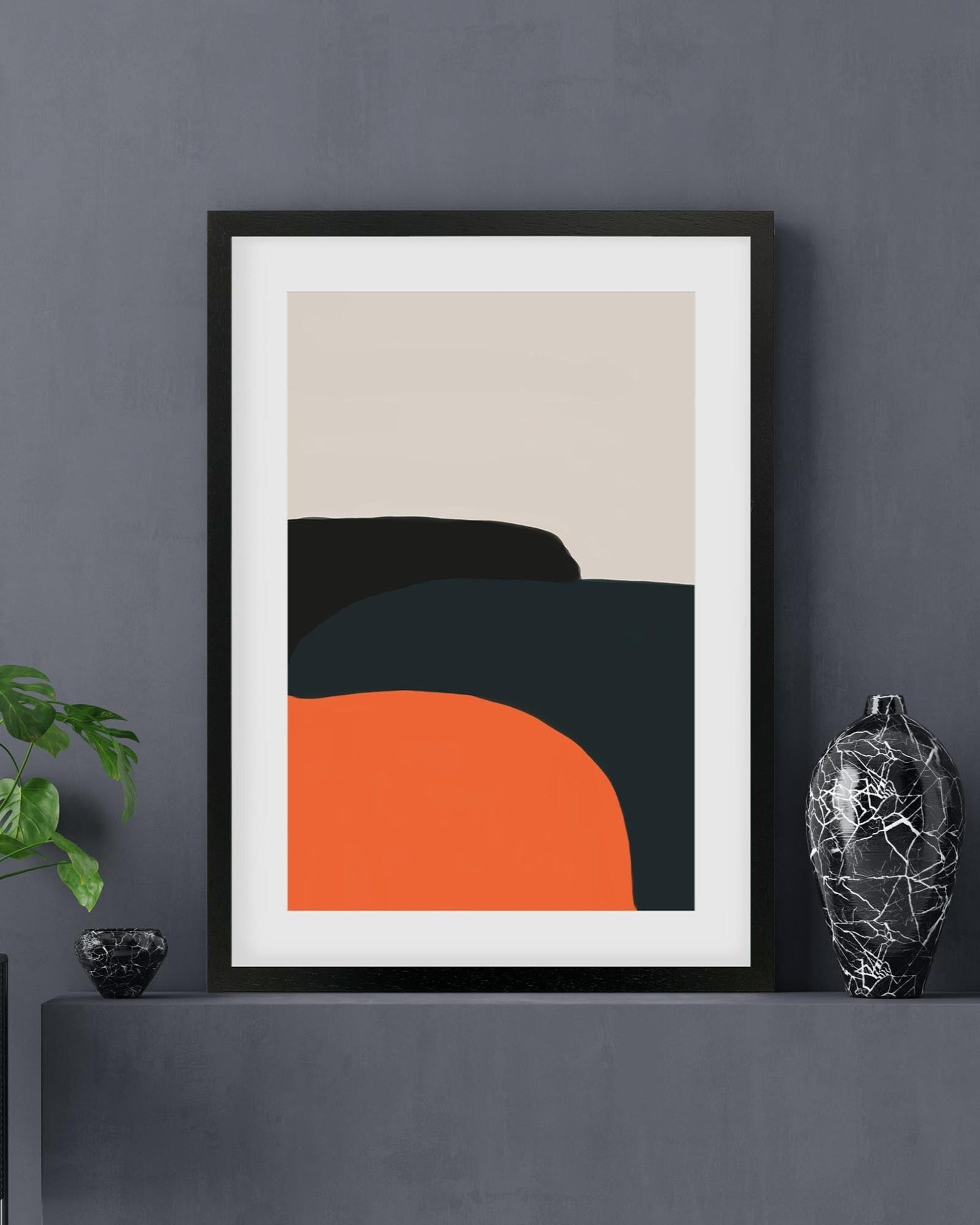 Framed abstract art print on a dark gray wall with decorative items.