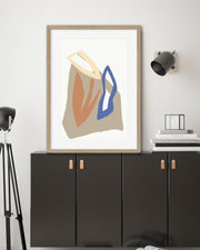 Abstract art print in a wooden frame on a wall above black cabinets.