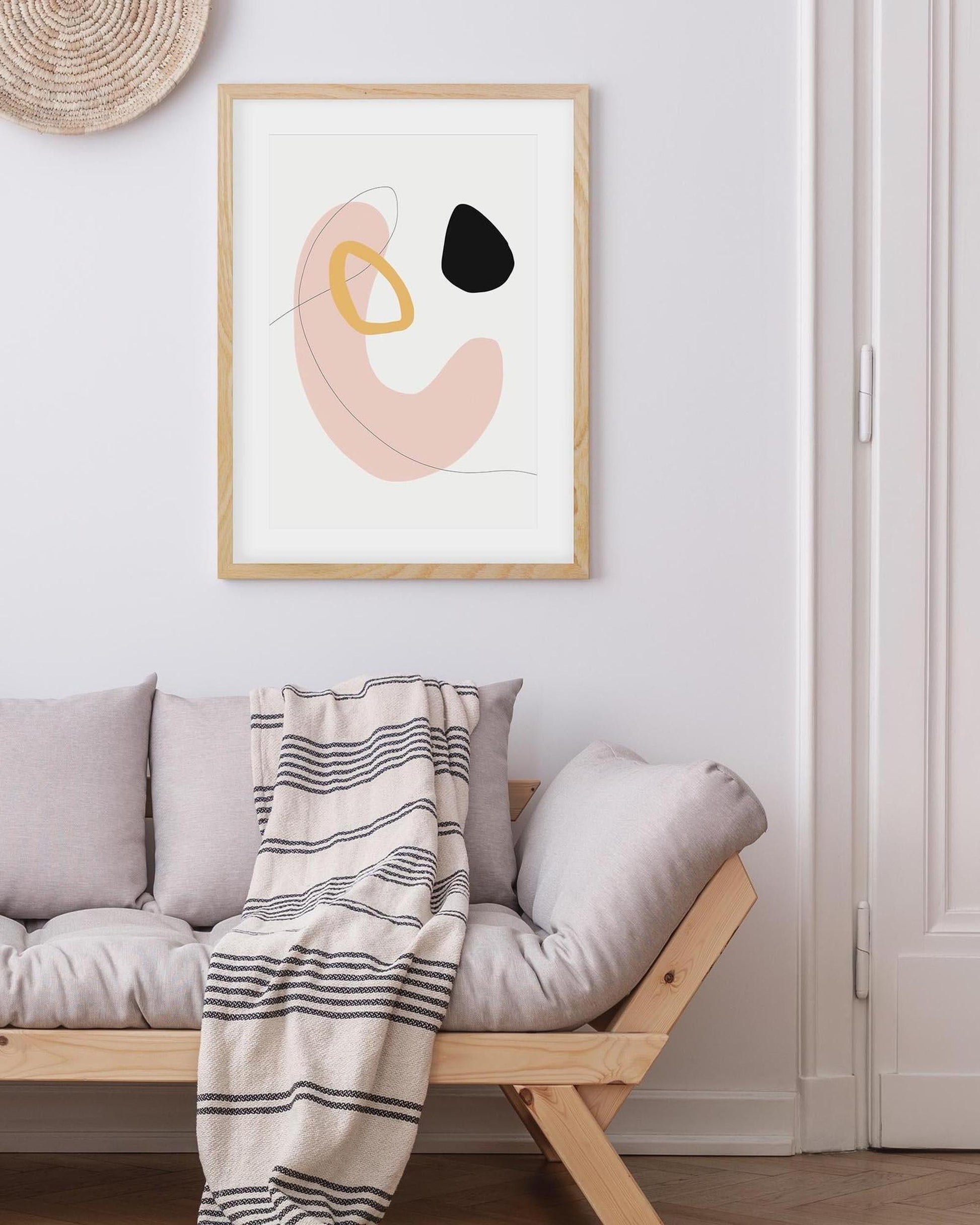 Abstract art print on a wall above a sofa with a striped blanket
