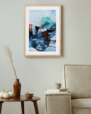 Framed abstract painting on a wall above a wooden side table with decorative items.