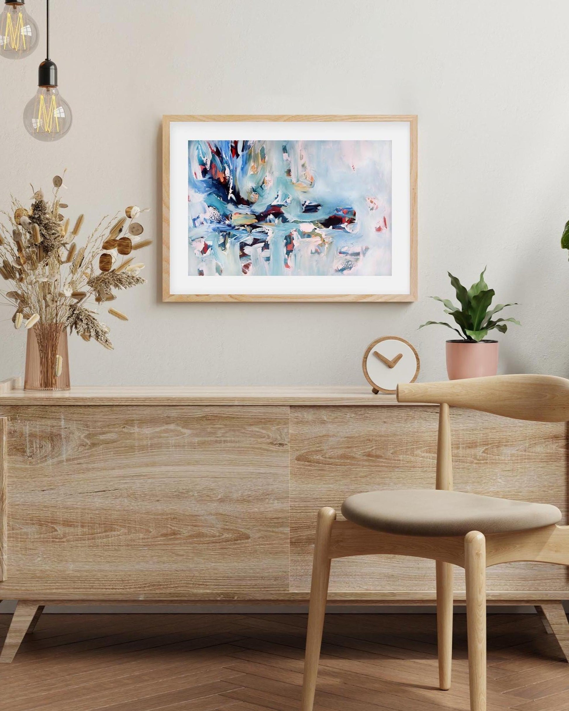 Wooden sideboard with chair, abstract painting, and plants in a room setting.