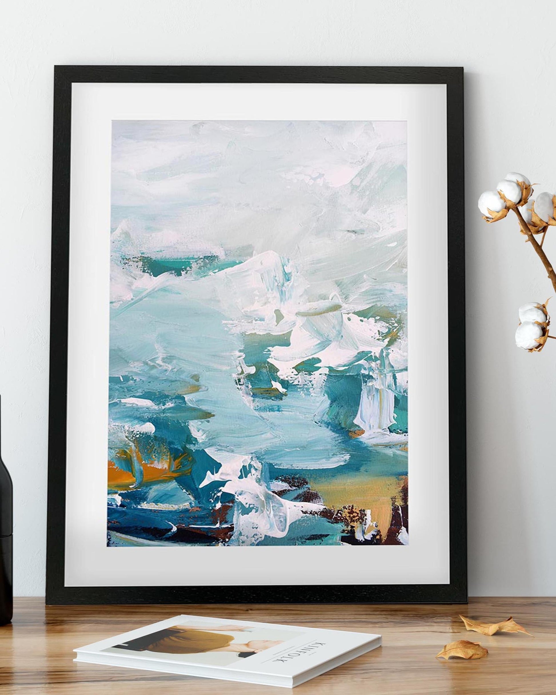 Framed abstract art print on a wooden surface with a white wall background