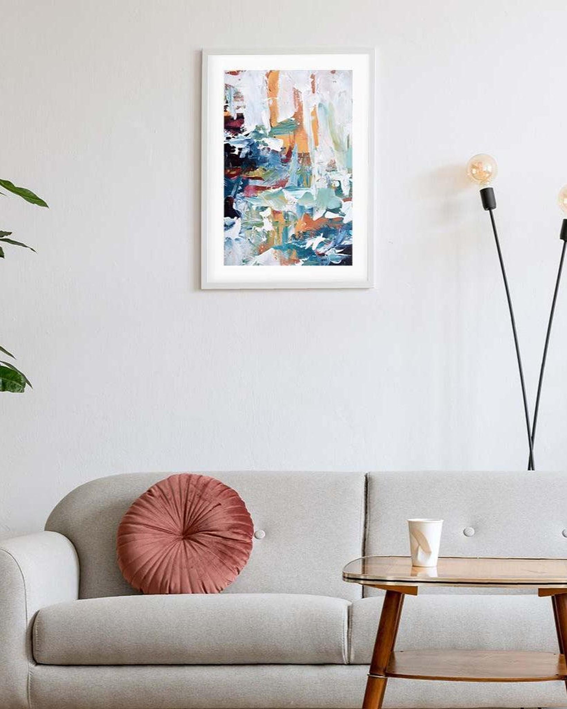 Living room with a gray sofa, pink pillow, and abstract art on the wall.