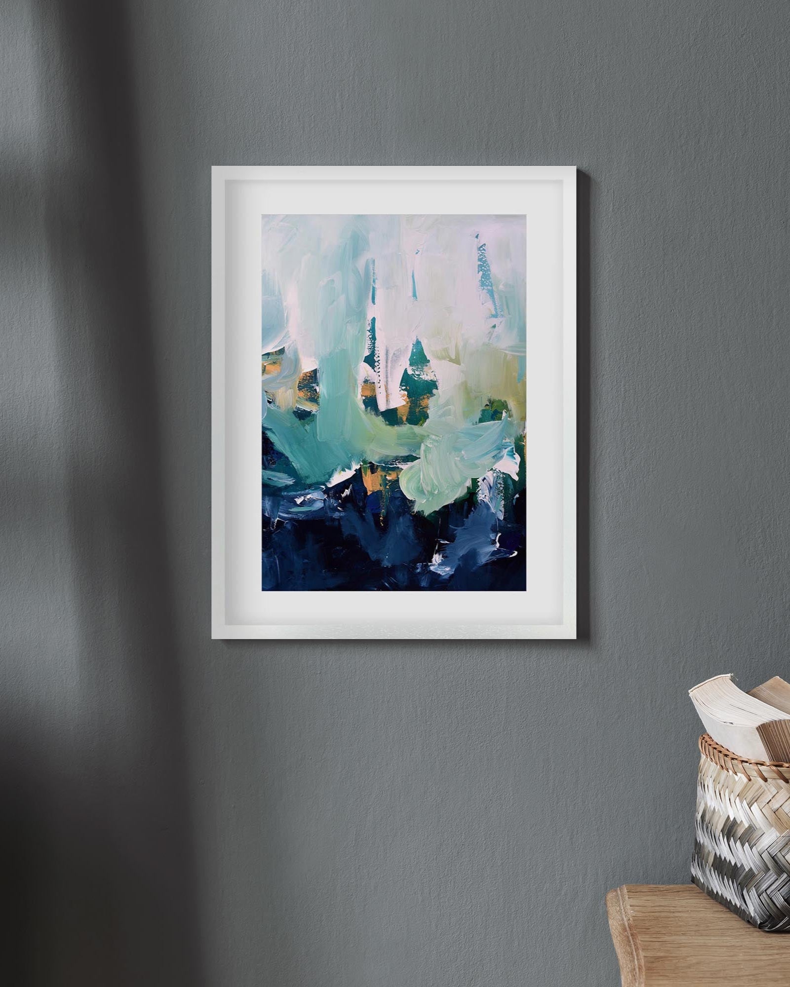 Framed abstract art print on a gray wall with a wooden ladder and basket in the foreground.