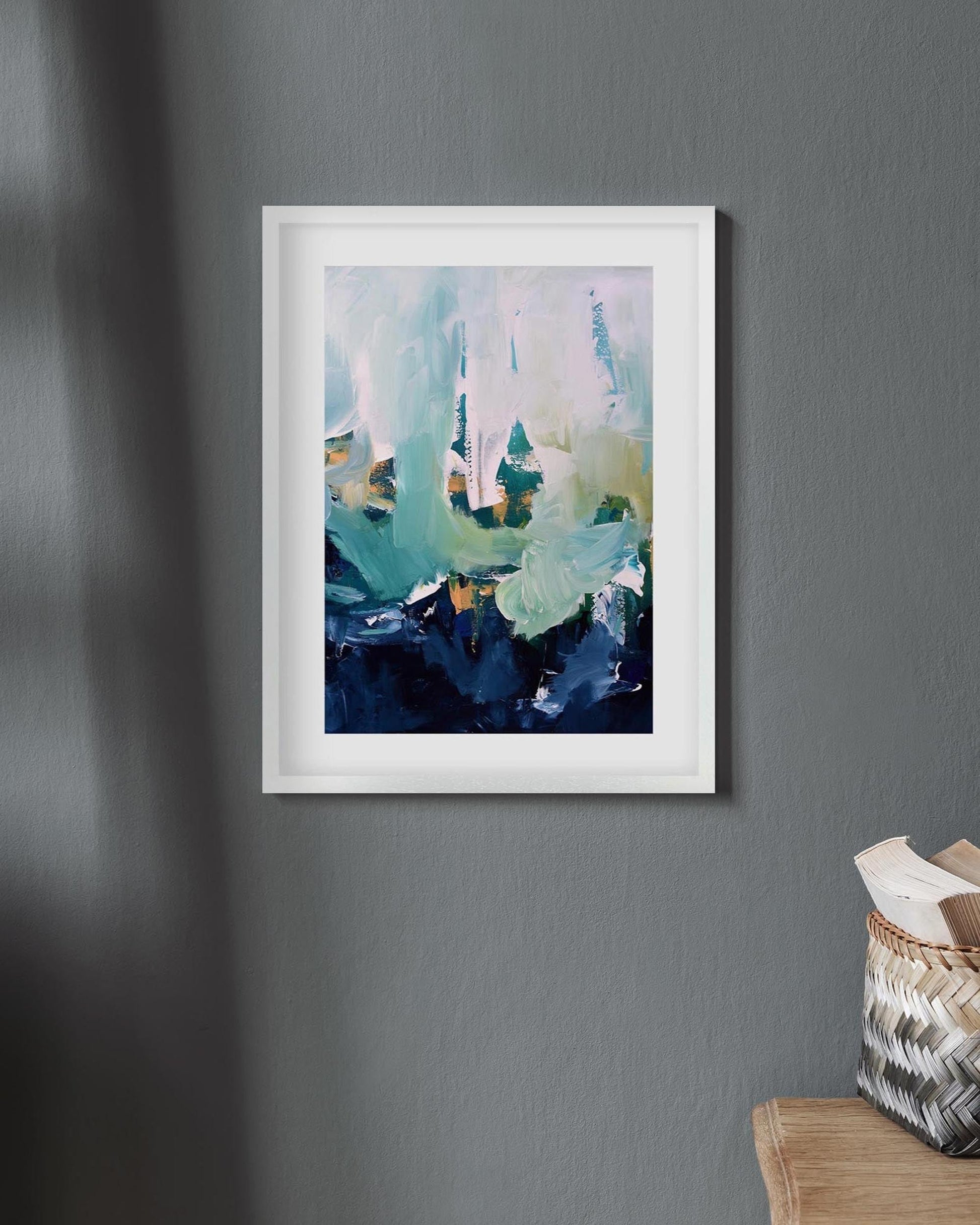 Framed abstract art print on a gray wall with a wooden ladder and basket in the foreground.