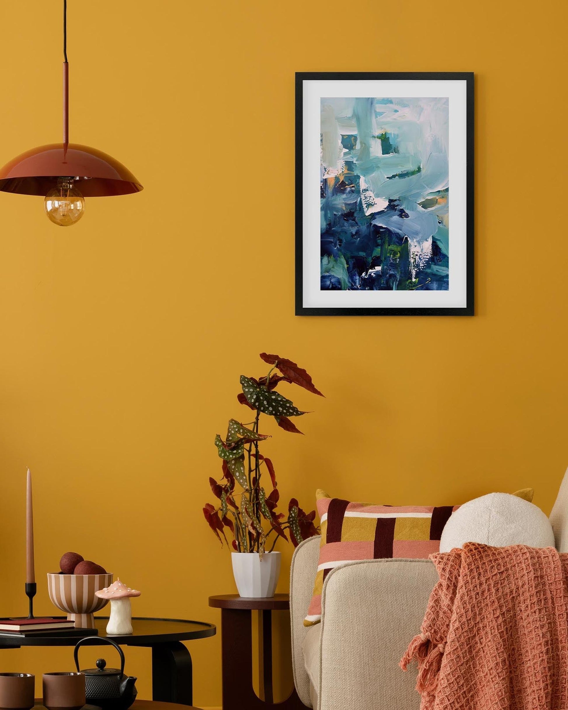 Living room with yellow walls, a framed abstract painting, and decorative items.
