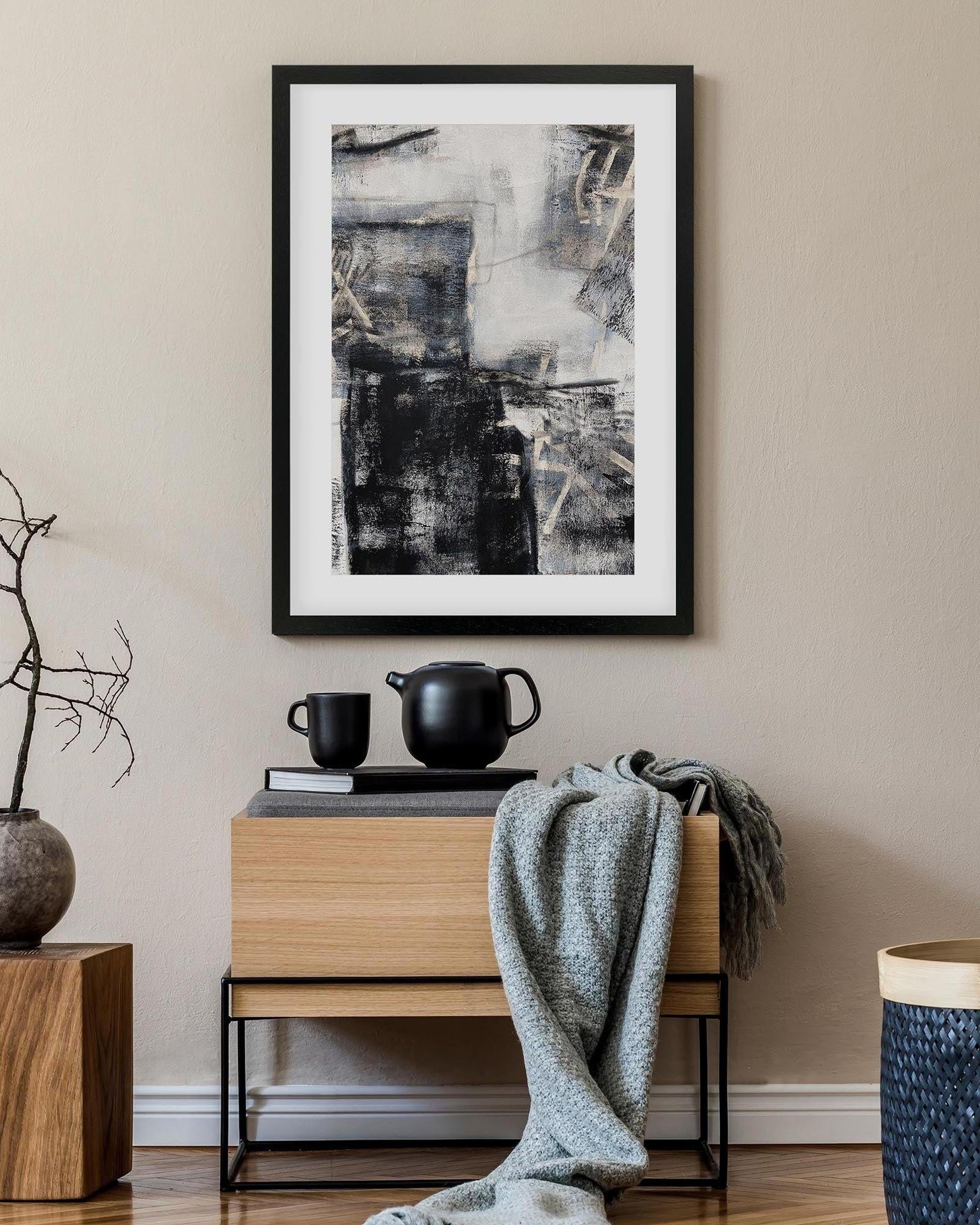 Framed abstract art on a wall above a wooden bench with decor items.