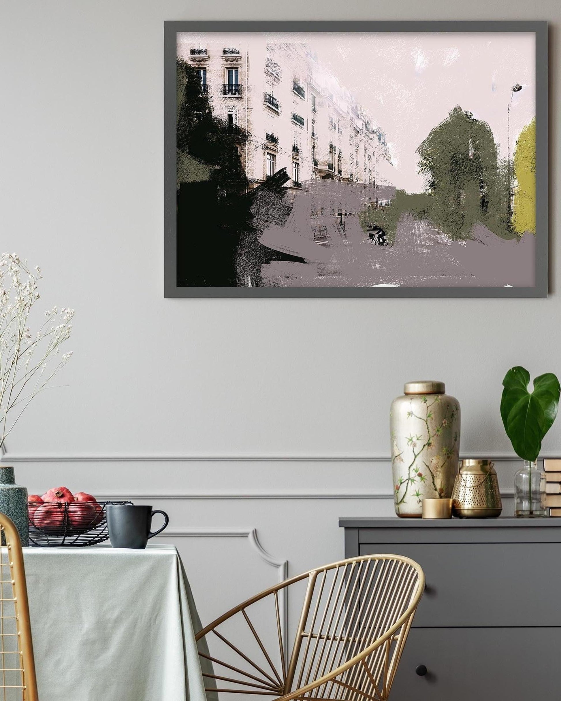 Framed artwork of a city street scene on a wall above a table with decorative items.