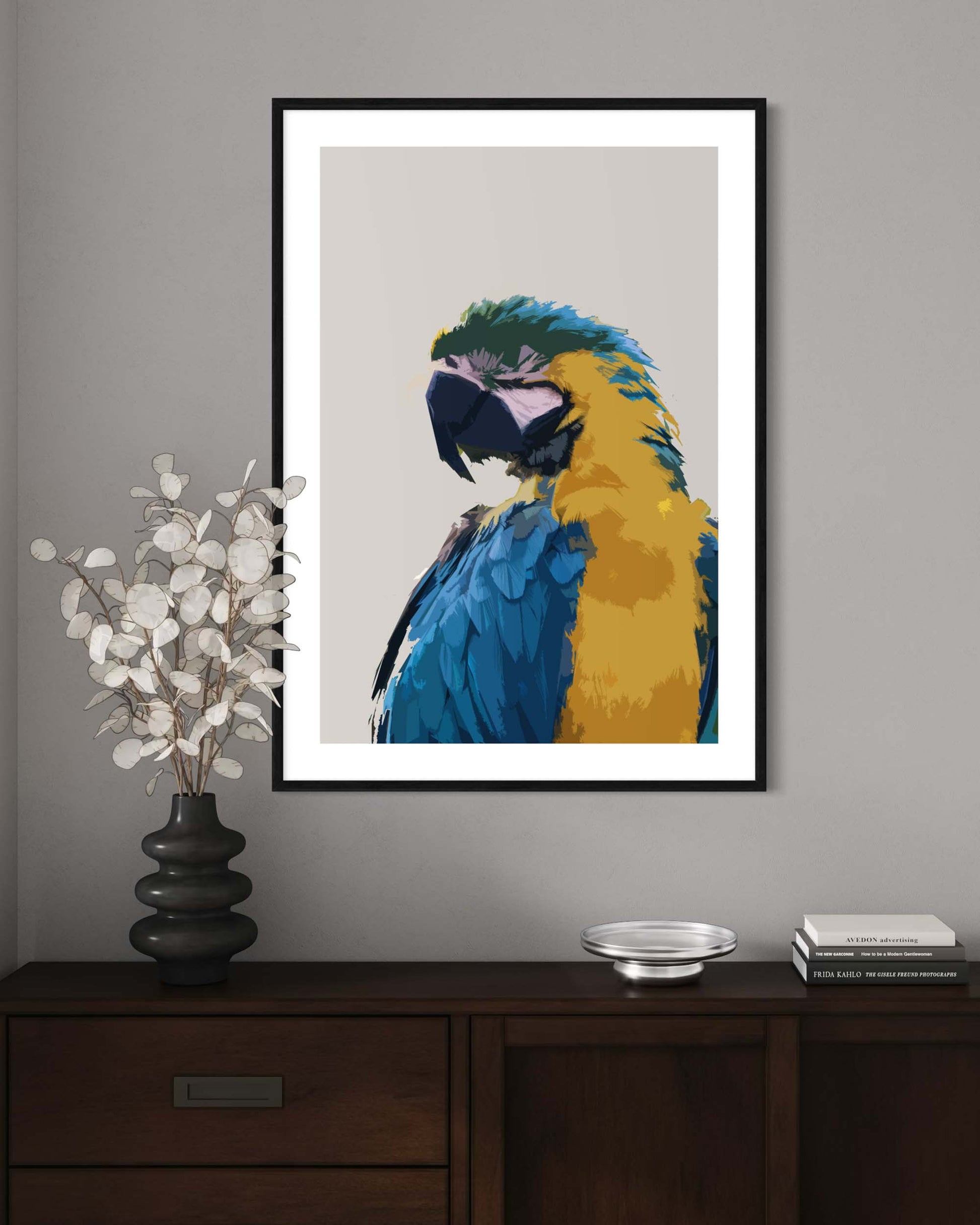 Framed artwork of a colorful parrot on a wall above a wooden cabinet.