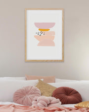 Framed abstract art print on a wall above a bed with colorful pillows.