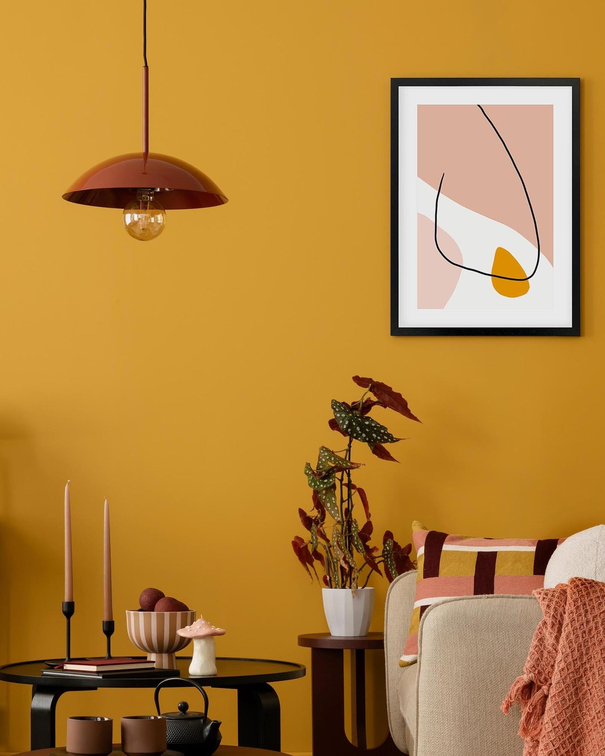 Living room with yellow walls, a framed abstract art piece, and decorative items.