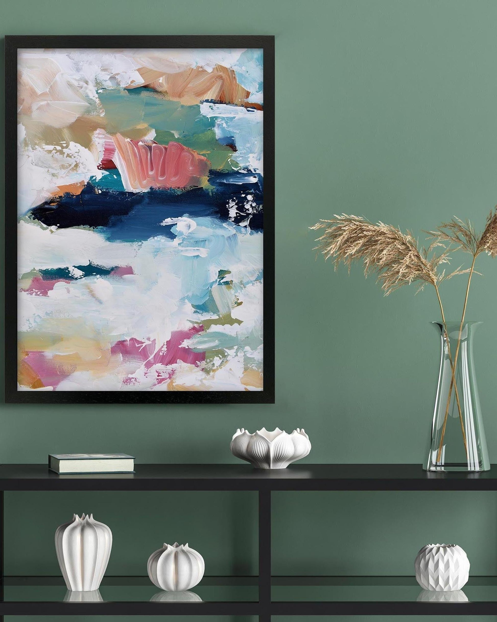 Framed abstract painting on a green wall with decorative items below.