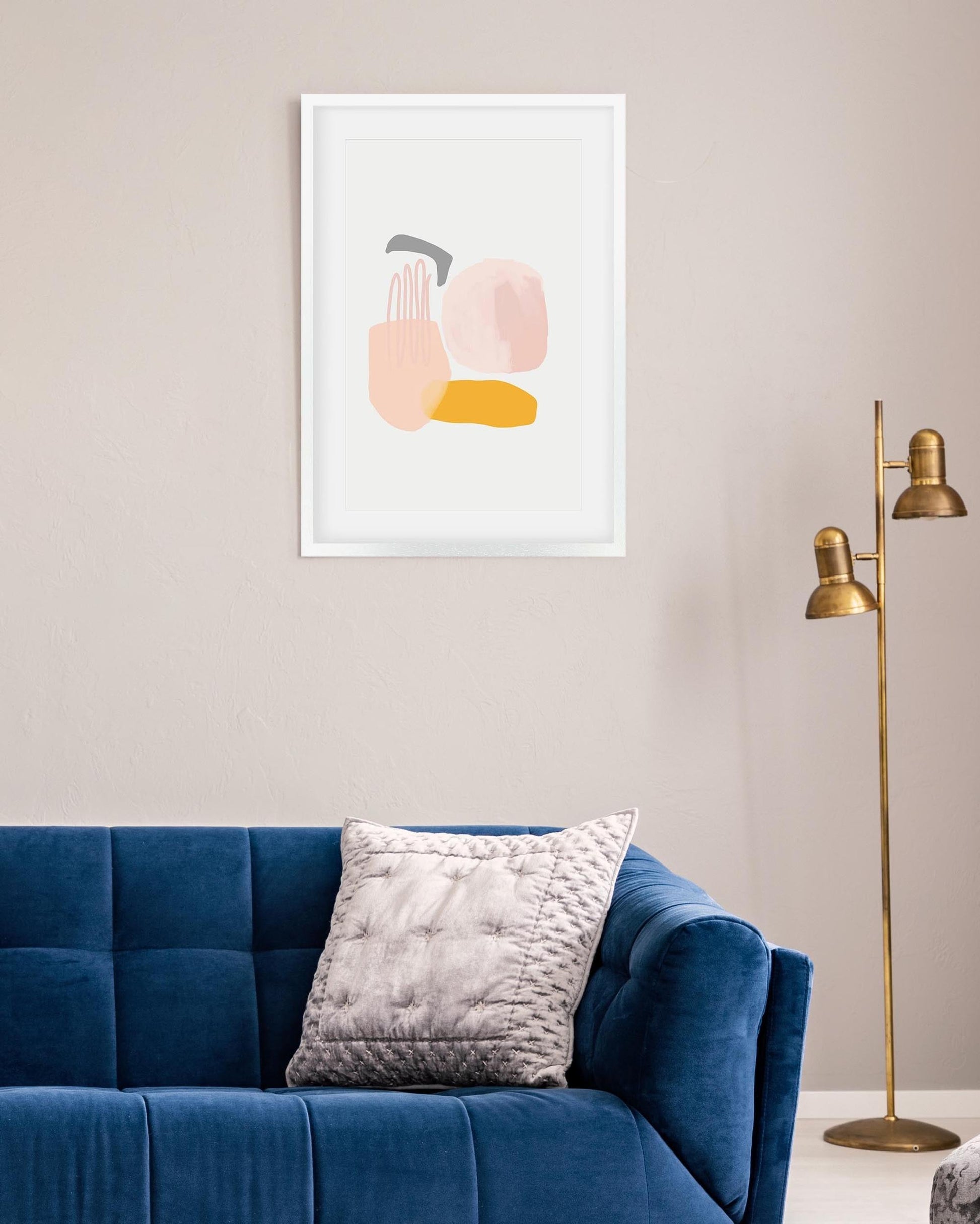 Abstract art print on a wall above a blue sofa with a gold floor lamp.