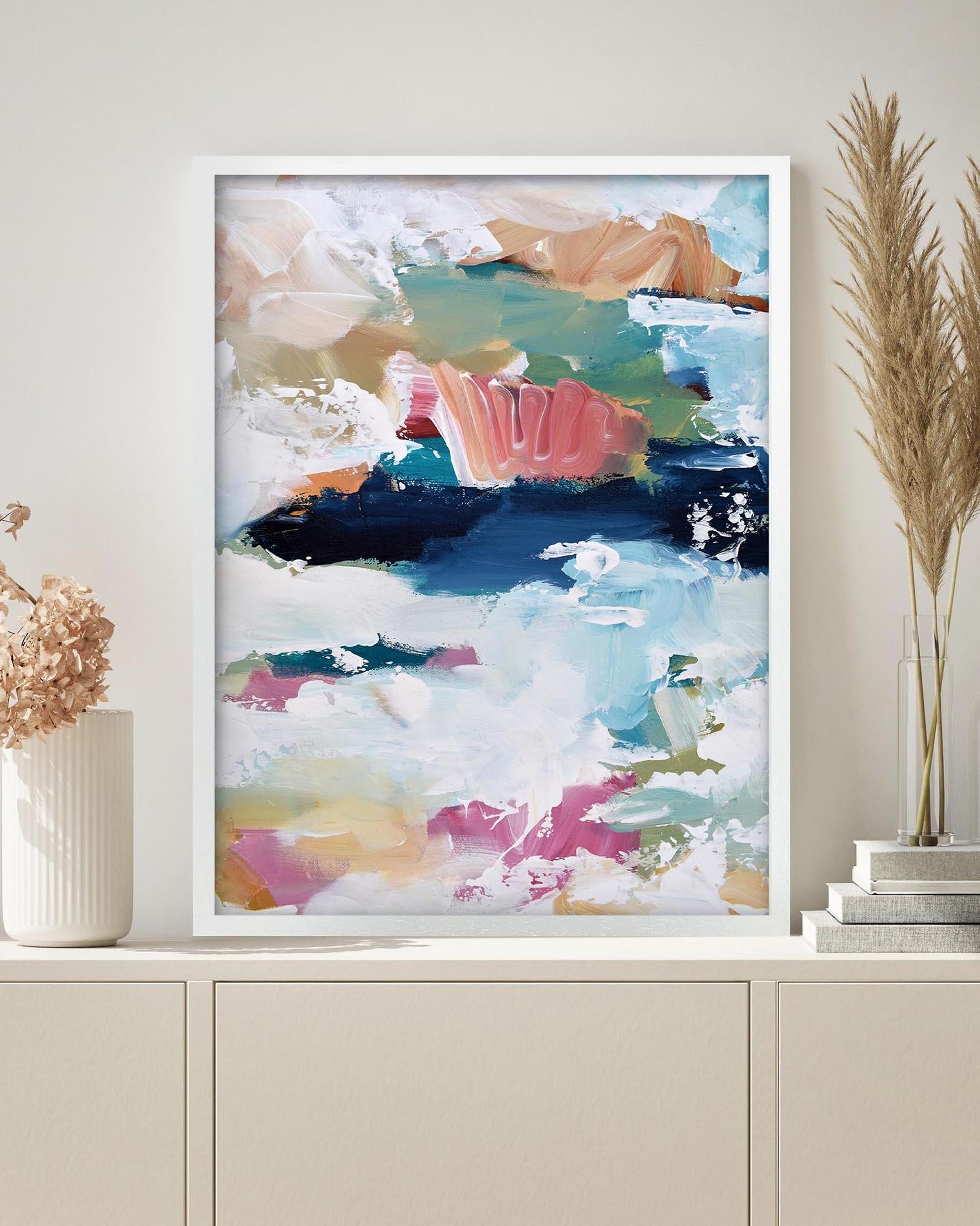 Abstract art print in a white frame on a wall above a cabinet.
