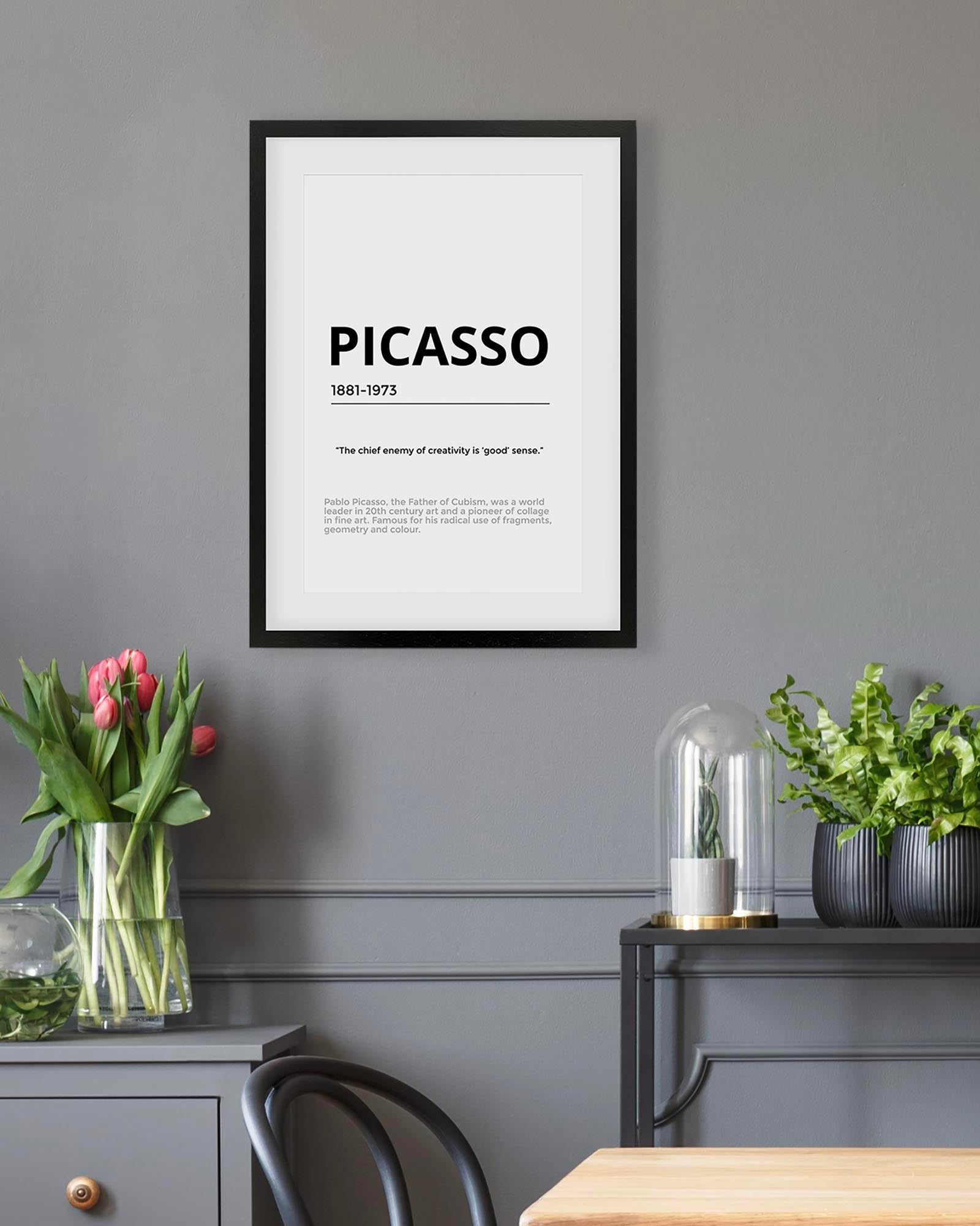 Framed Picasso quote on a gray wall with decorative elements.