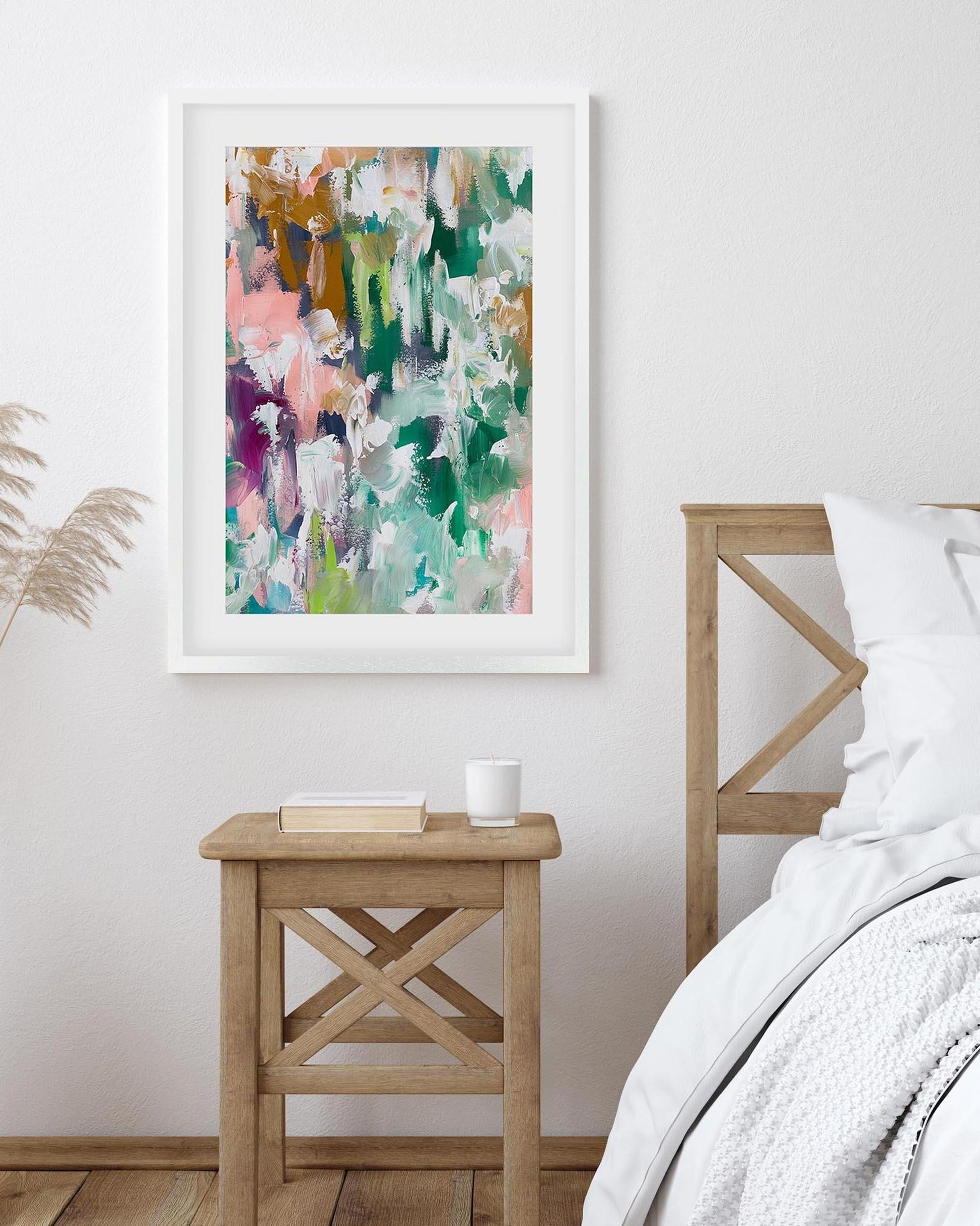 Framed abstract art print on a wall above a wooden side table in a bedroom.