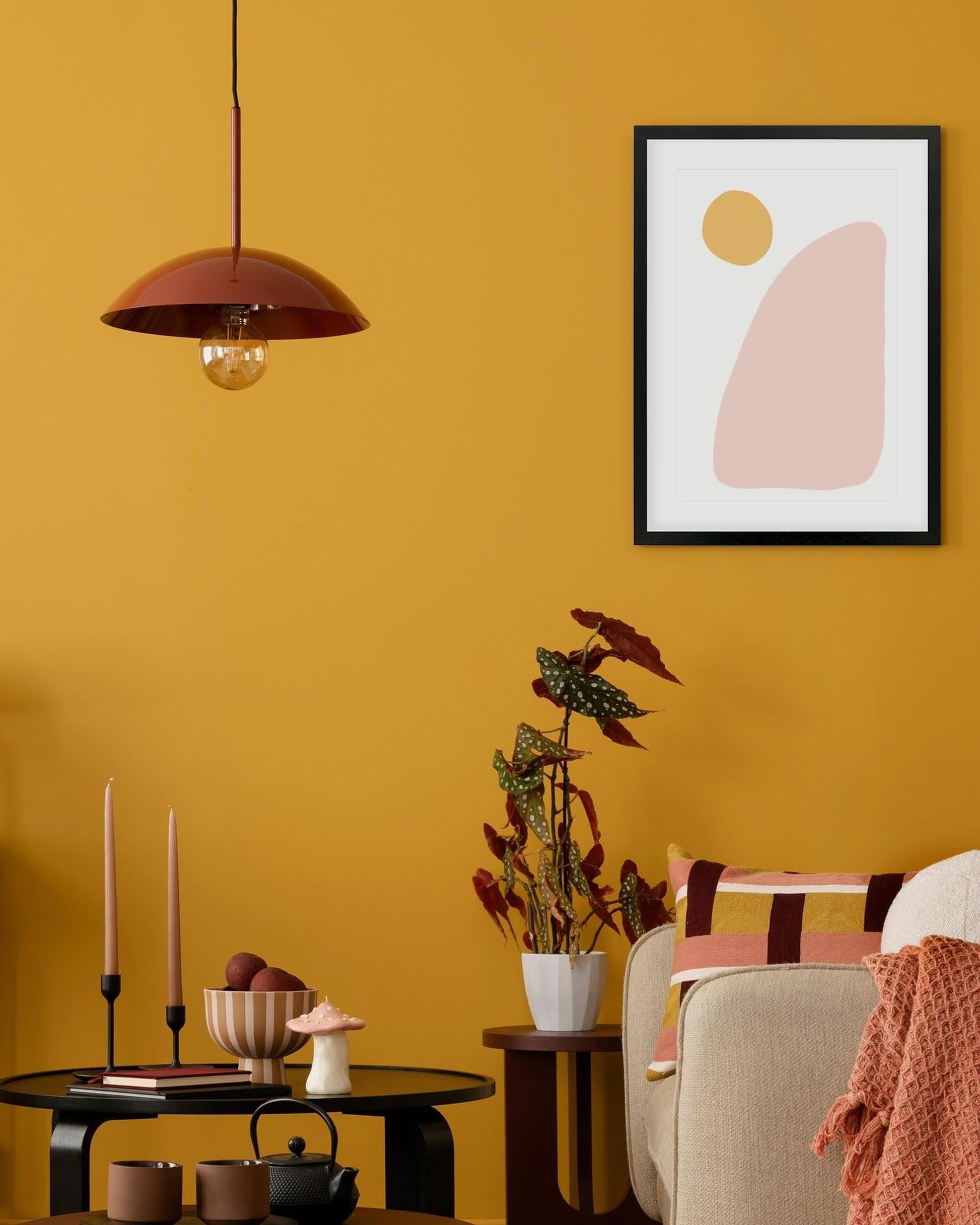 Living room with mustard yellow walls, a framed abstract art piece, and decorative items.