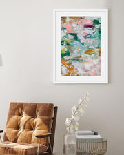 Framed abstract art on a wall above a brown armchair.