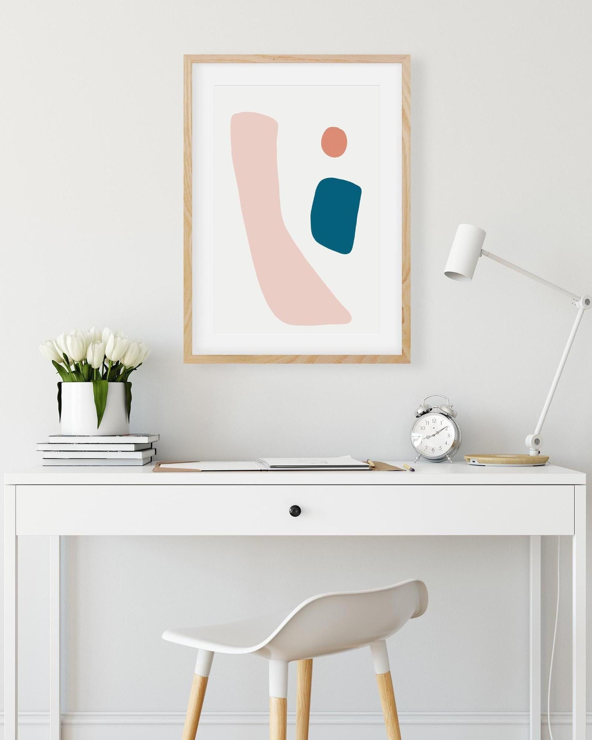Modern office desk with abstract art print, lamp, and decor items.