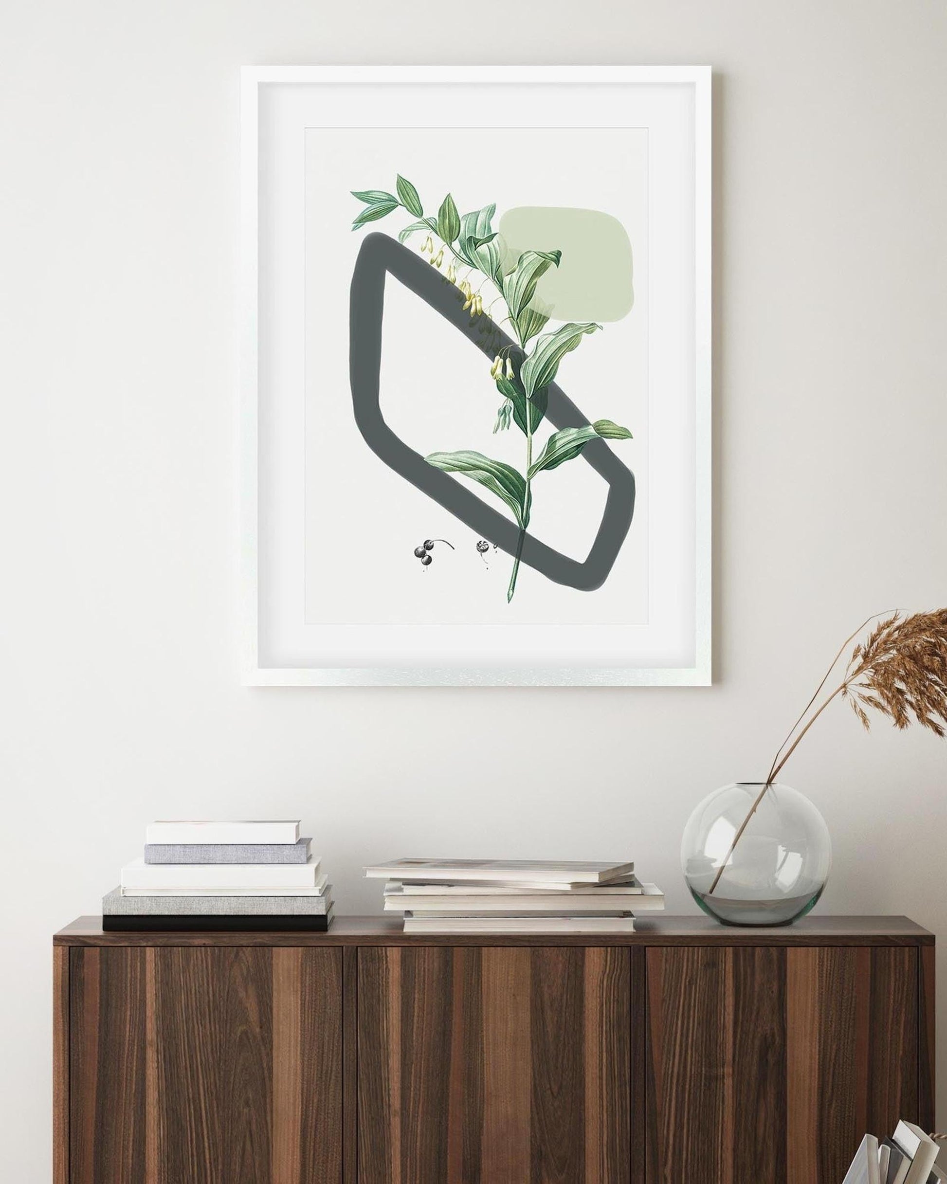 Framed artwork with a geometric design and plant elements on a wall above a wooden cabinet.