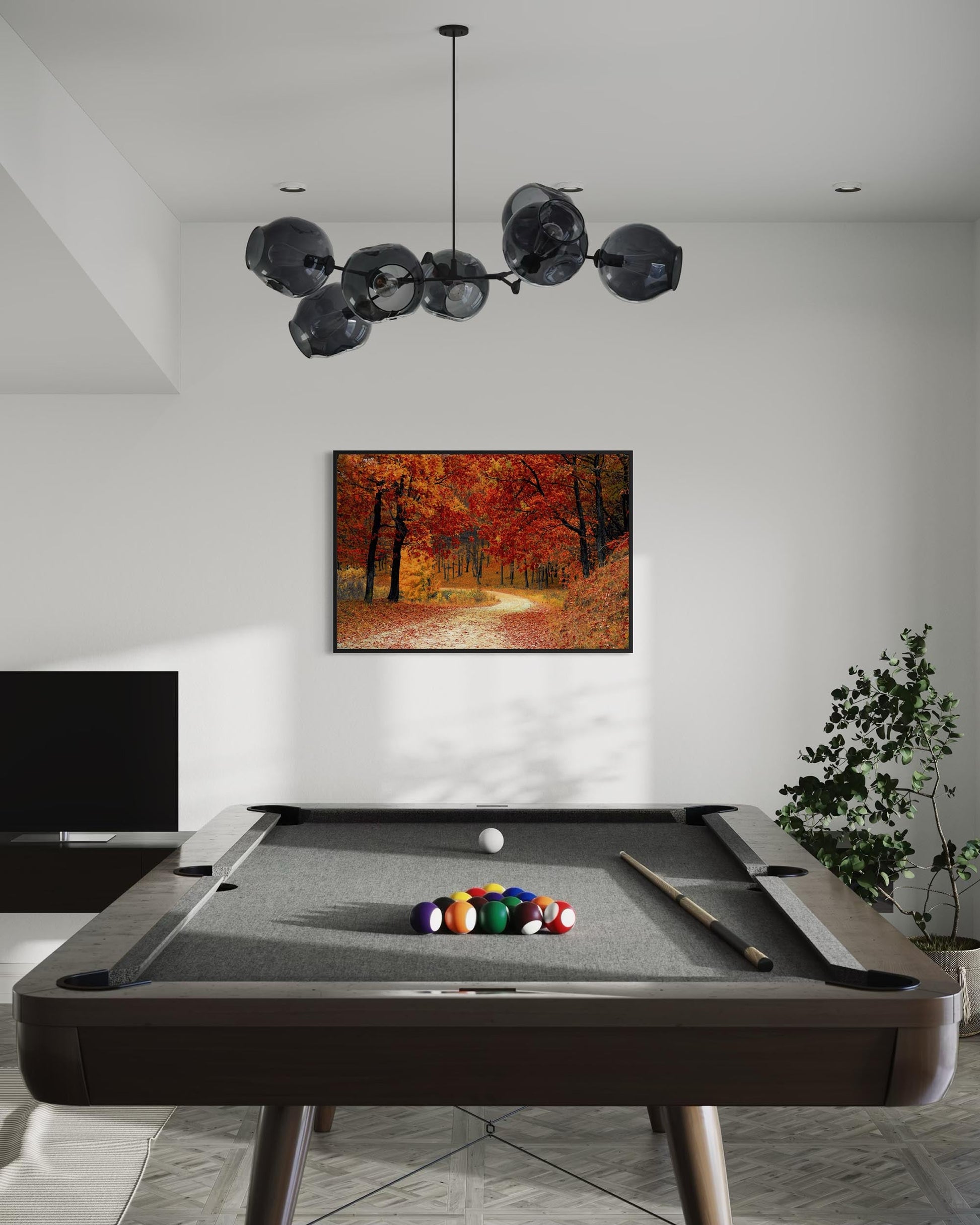 Modern pool table with colorful balls in a room with a chandelier and wall art.
