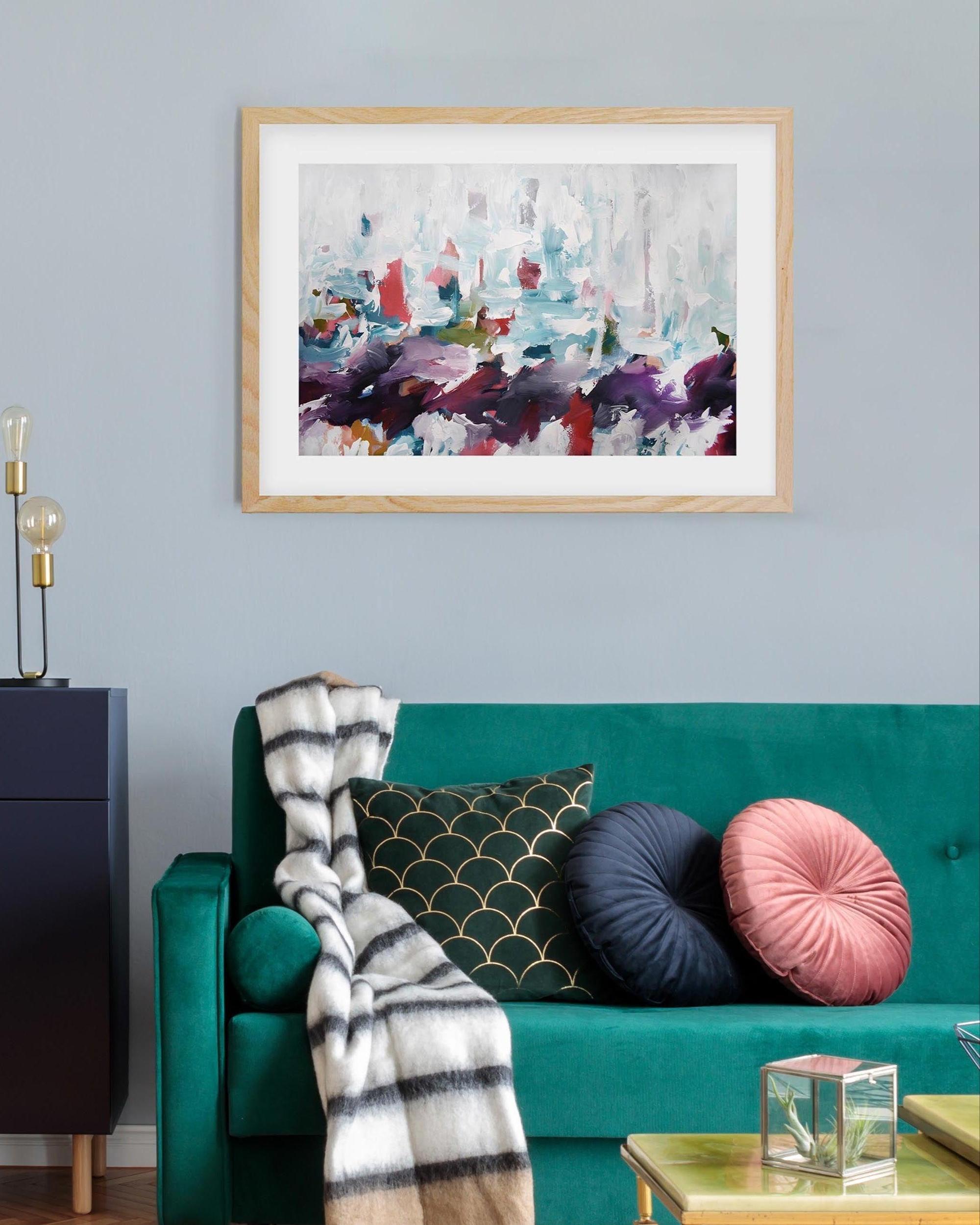 Living room with teal sofa, colorful pillows, and abstract art on the wall.