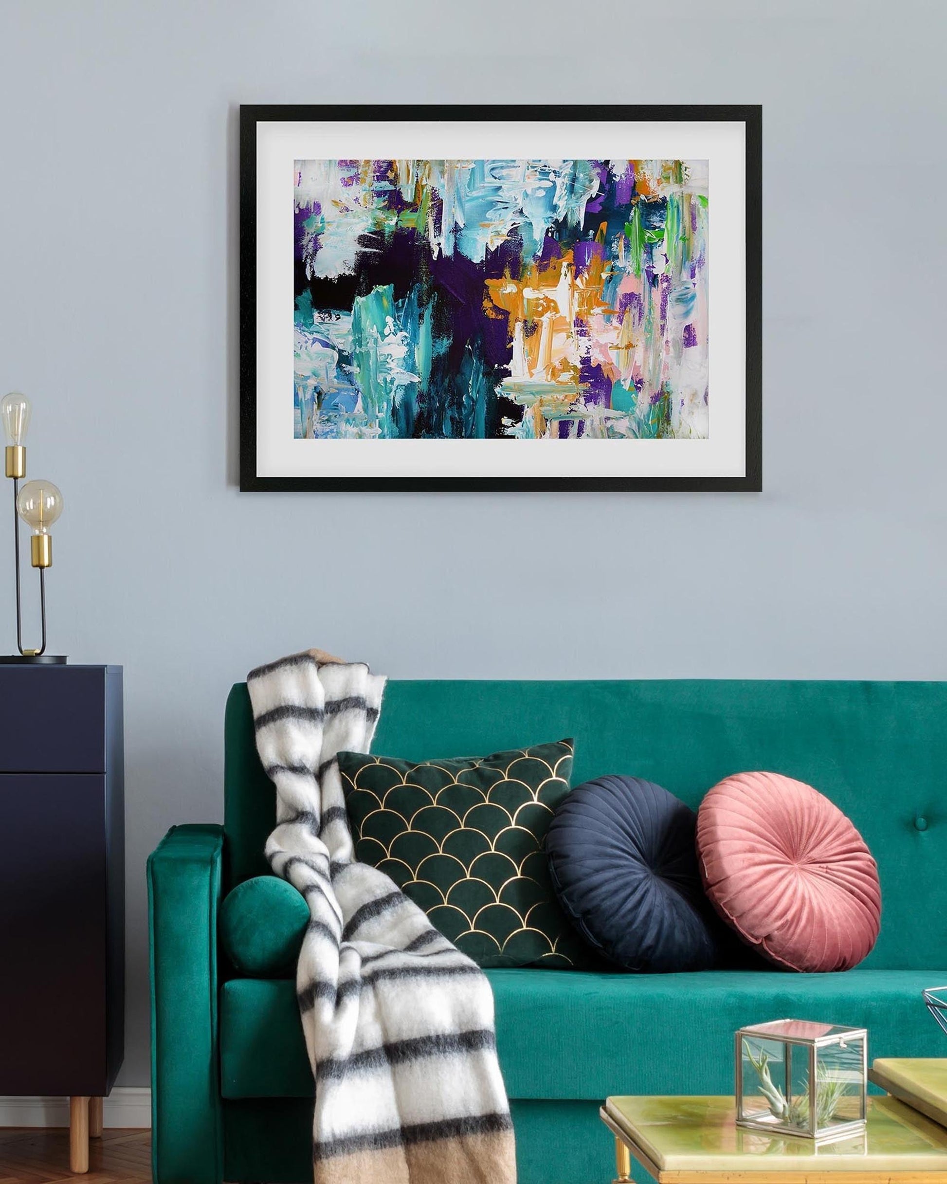 Living room with a teal sofa, colorful pillows, and abstract art on the wall.