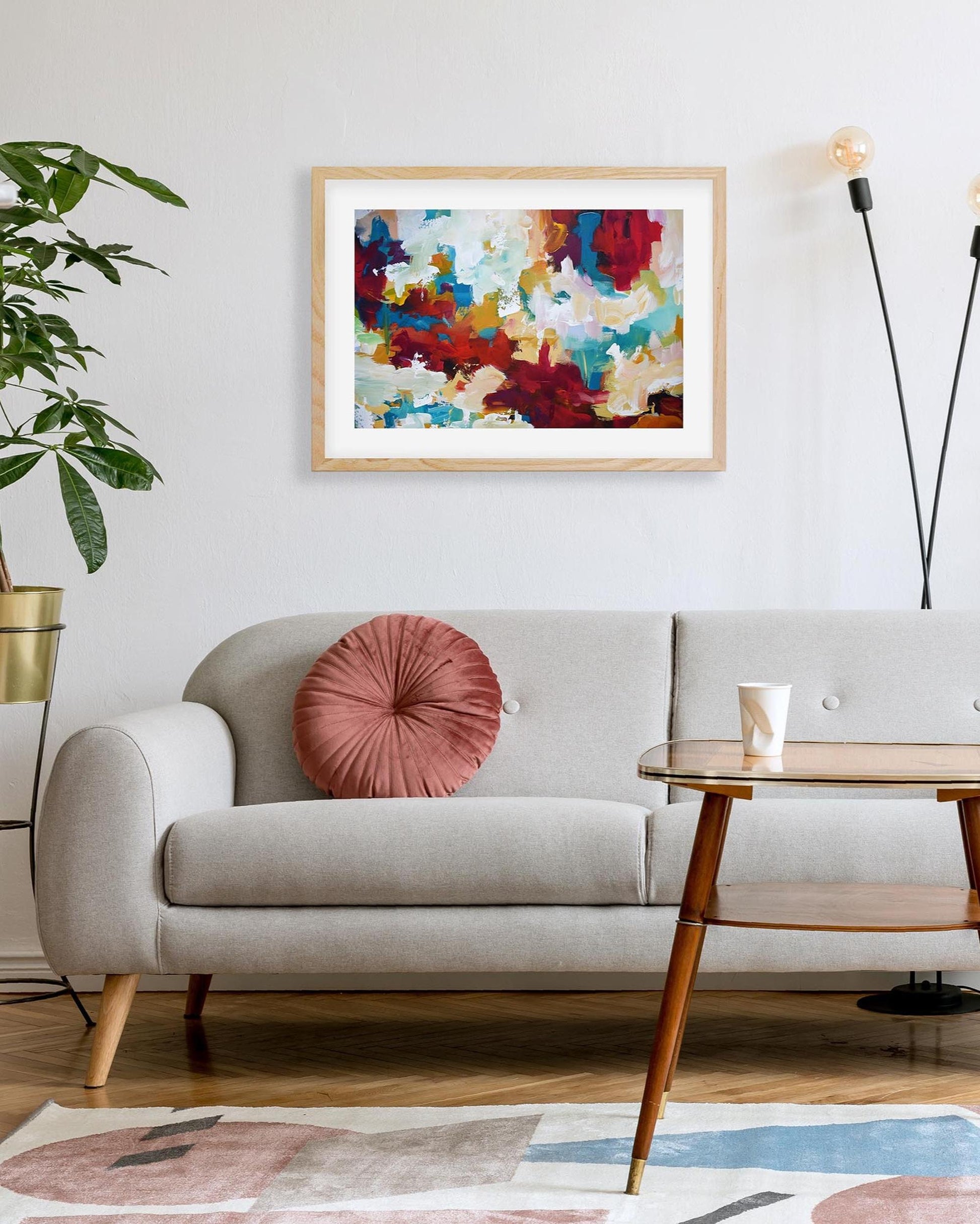 Living room with a gray sofa, pink pillow, and colorful abstract painting on the wall.